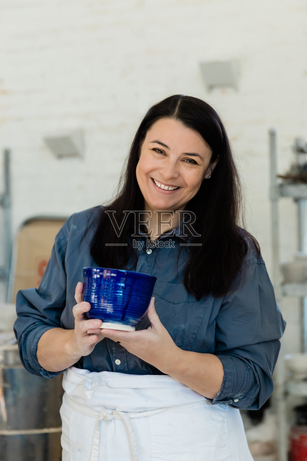 在艺术工作室里，创意陶艺家拿着一块未完成的粘土陶器照片摄影图片