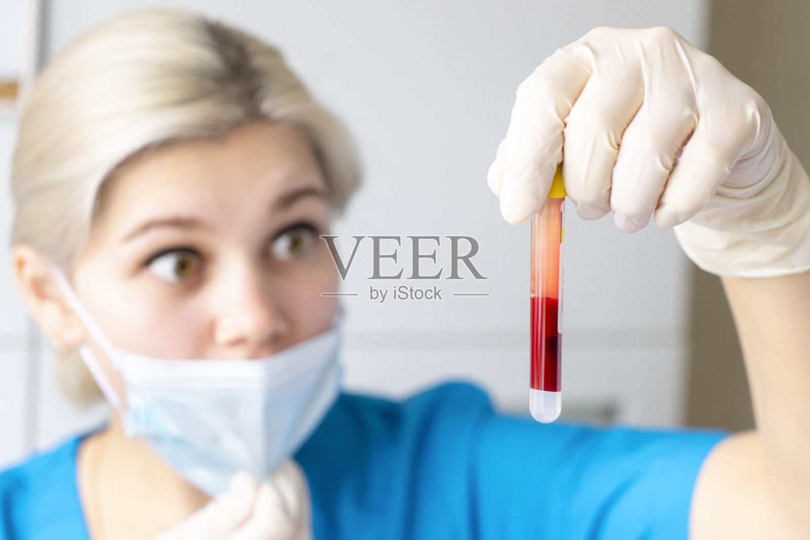 漂亮的白种护士戴着口罩和乳胶手套拿着血液试管检查冠状病毒或其他感染照片摄影图片