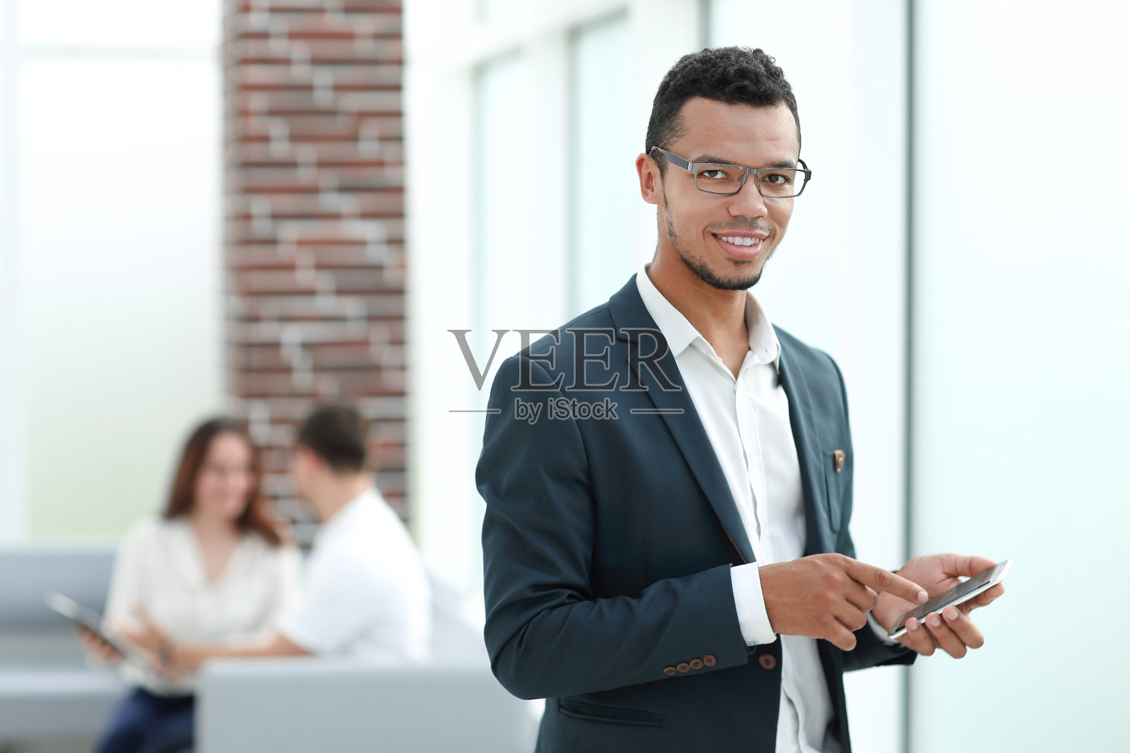 在现代办公室使用智能手机的年轻商人照片摄影图片