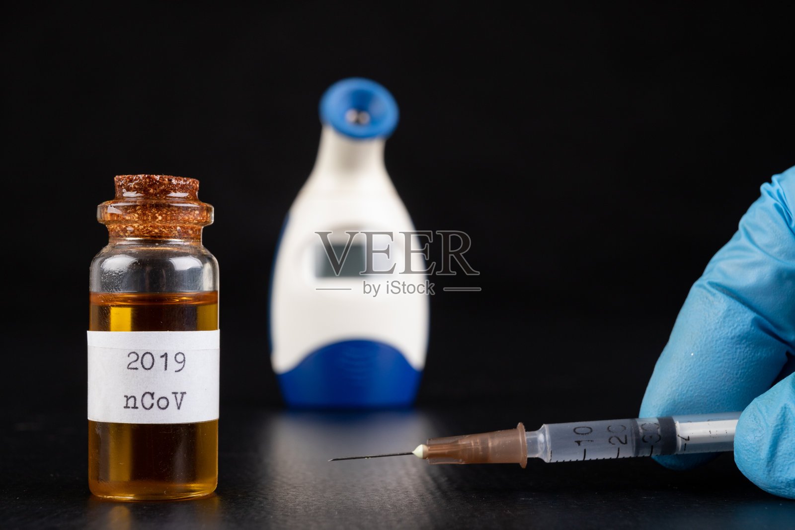 桌子上的玻璃瓶、带针头的注射器和温度计，实验室中的严重流感病毒，深色背景照片摄影图片