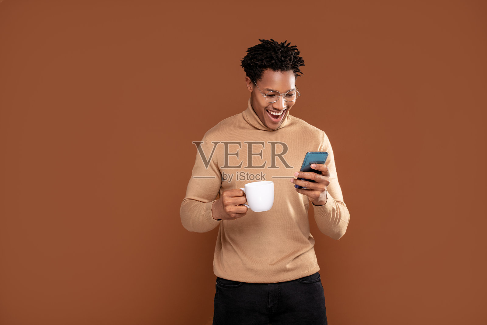 非洲男人用手机喝咖啡。照片摄影图片