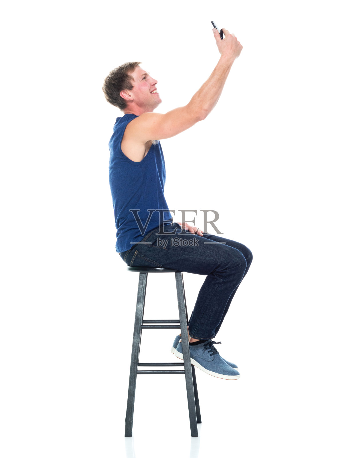 白种人年轻男性摄影休息穿着牛仔裤和使用手机照片摄影图片