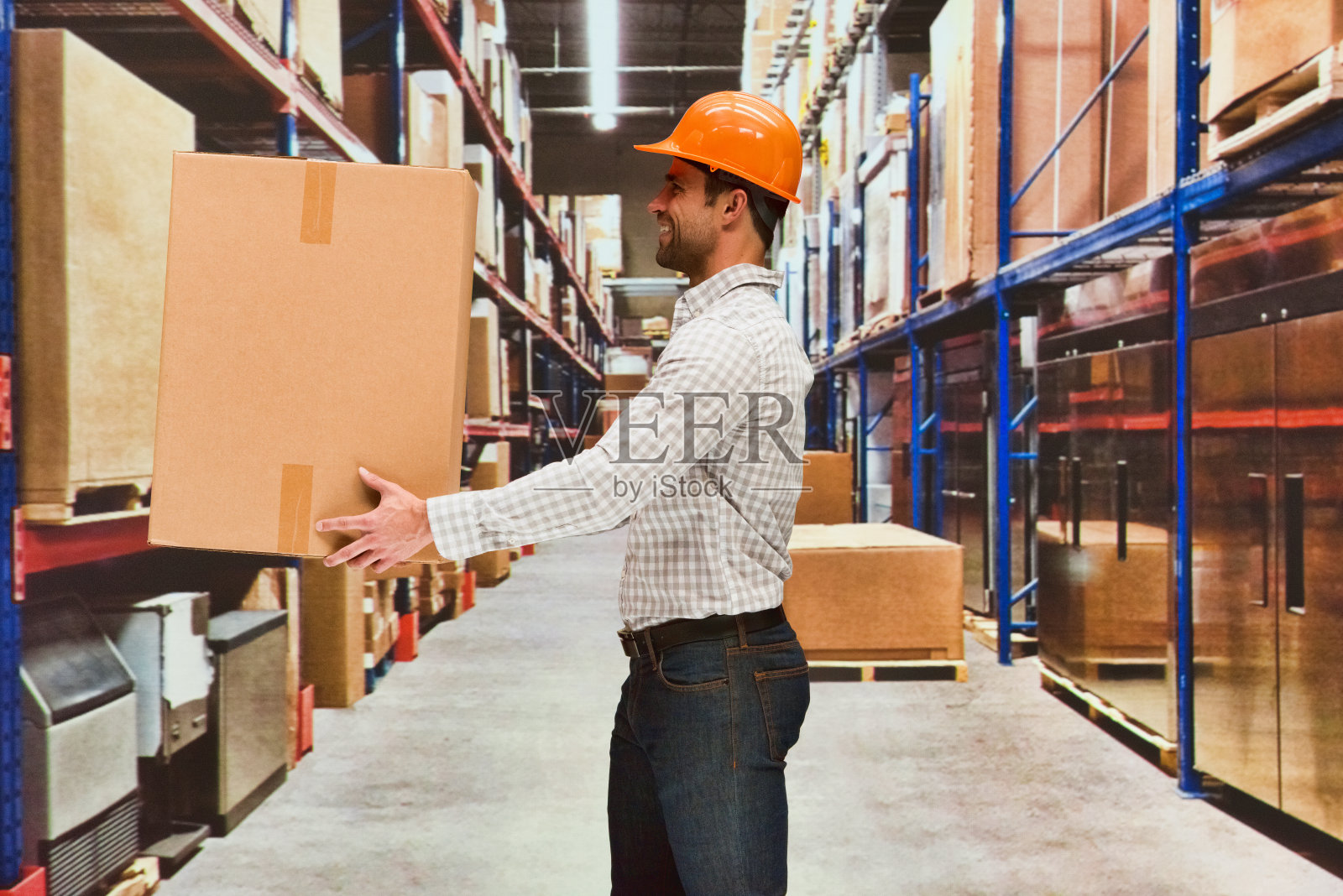 男摄影站在工厂商品前，戴着安全帽，拿着包裹照片摄影图片