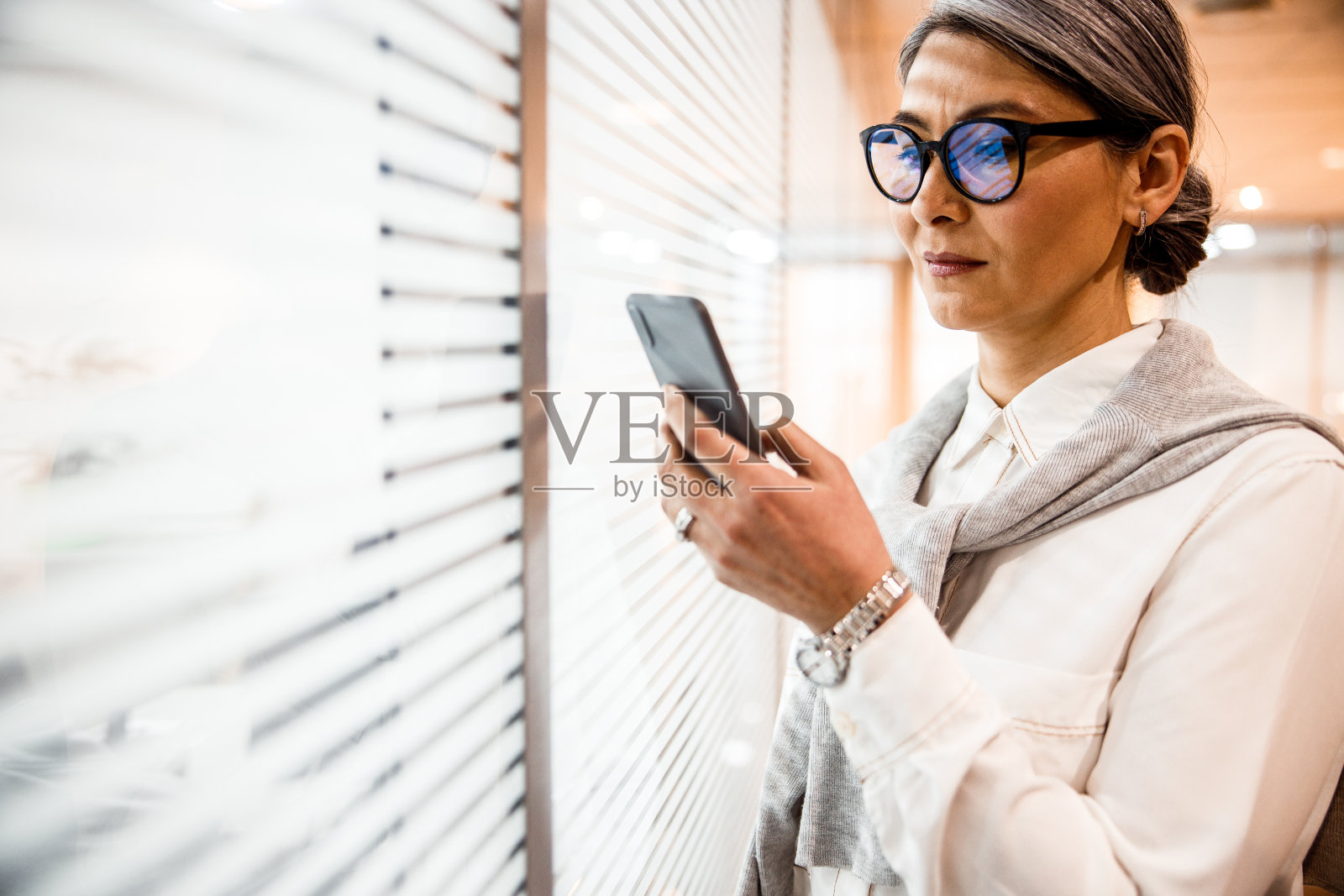 在办公室库存照片中使用智能手机的女人照片摄影图片