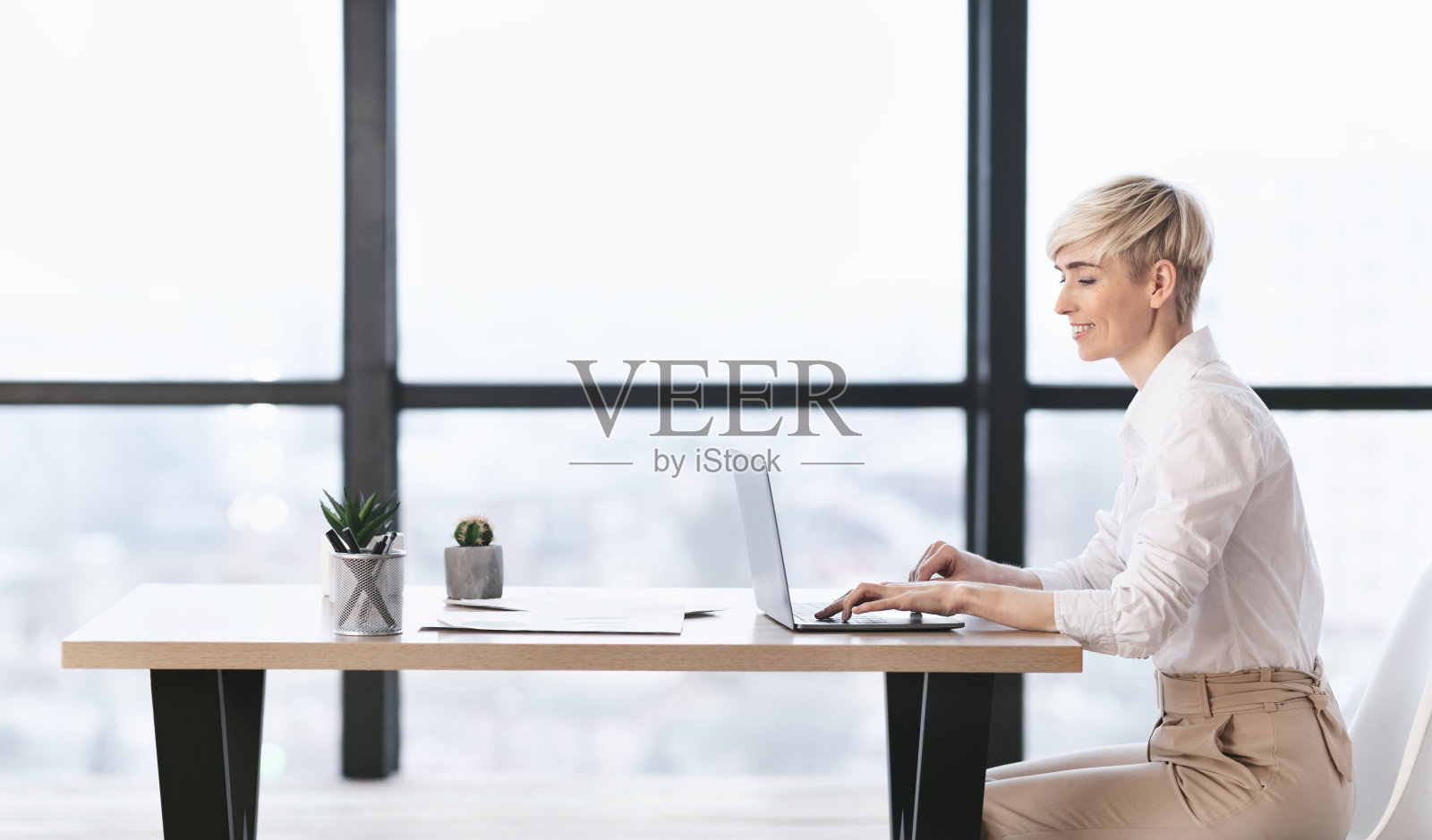 成功的女商人坐在办公室里用笔记本电脑工作照片摄影图片