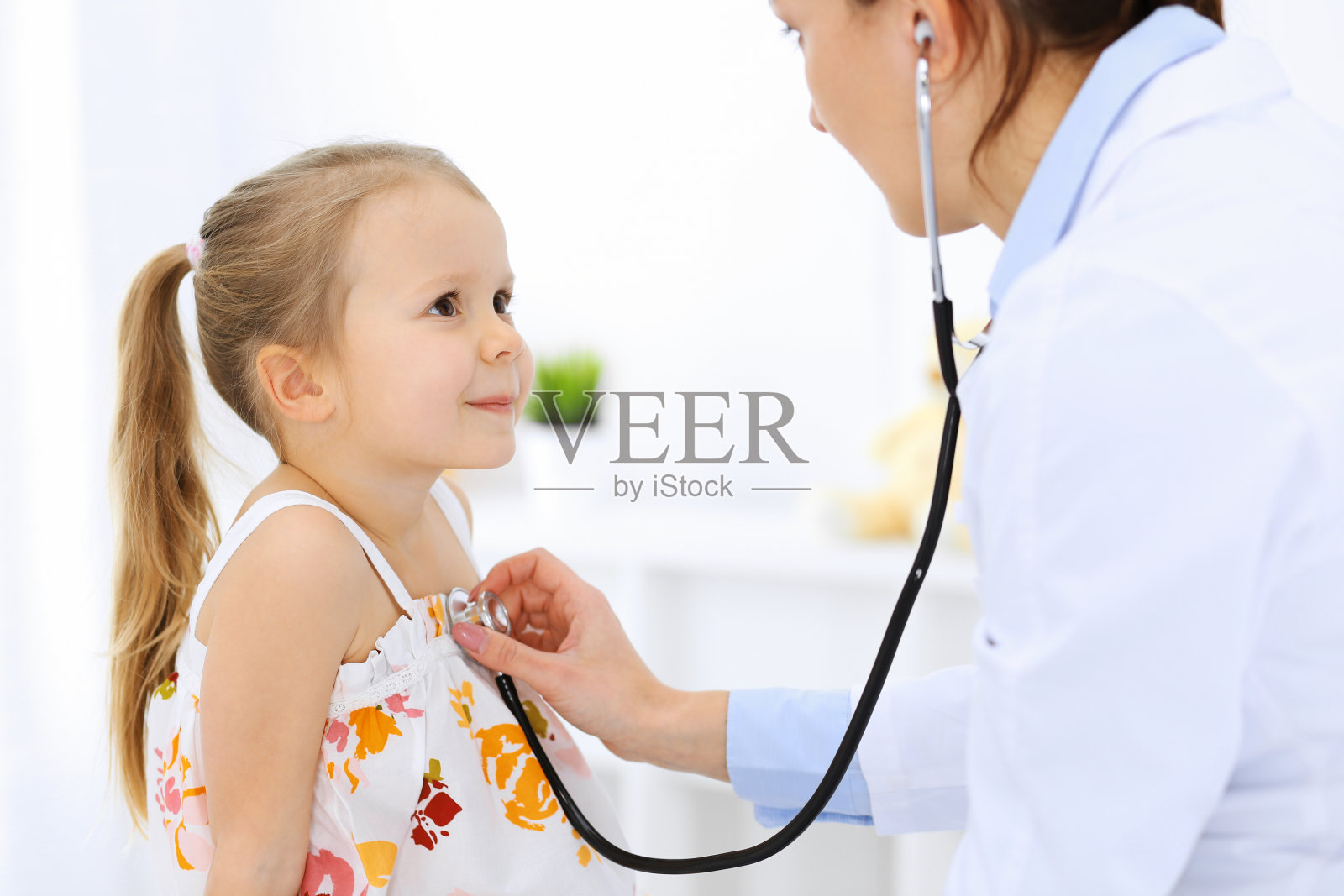 医生正在用听诊器检查一个小女孩。开心微笑的孩子病人在平时的医疗检查。医学和保健概念照片摄影图片