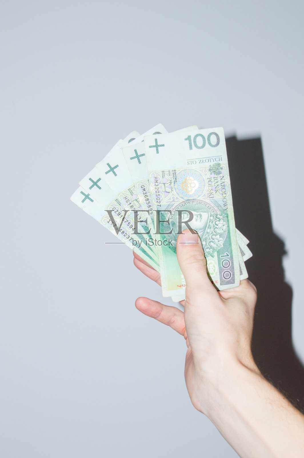 手里拿着100兹罗提的钞票。照片摄影图片