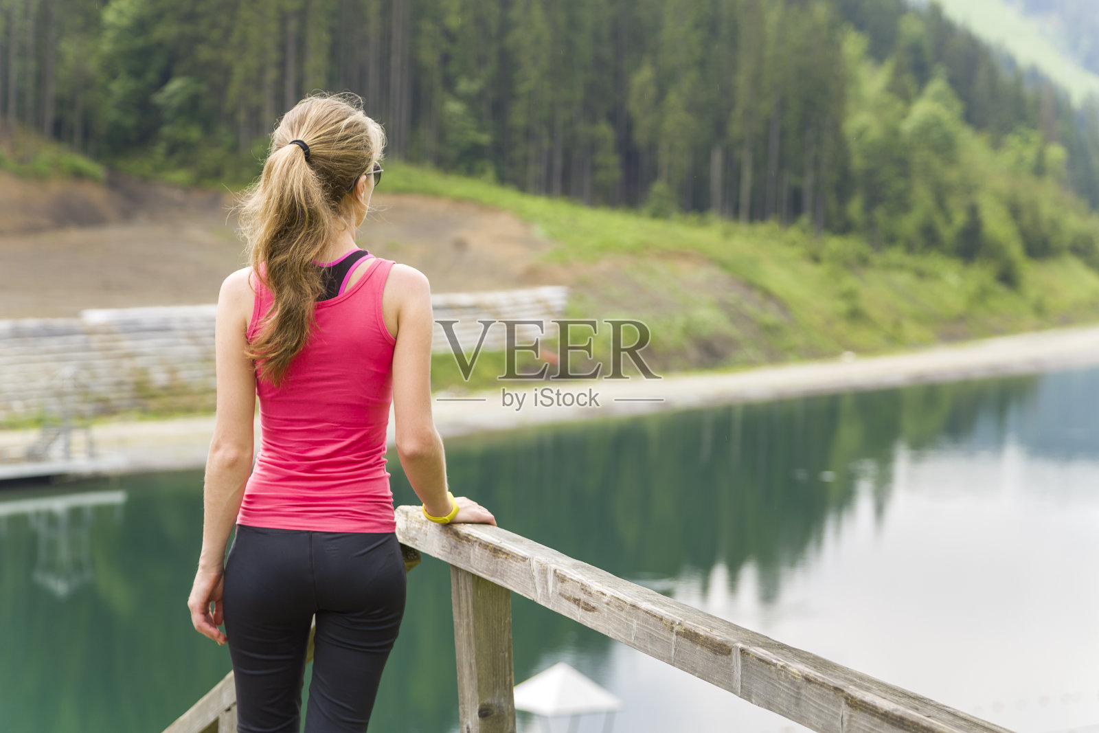 在山区大湖附近欣赏风景的运动型女子背影照片摄影图片