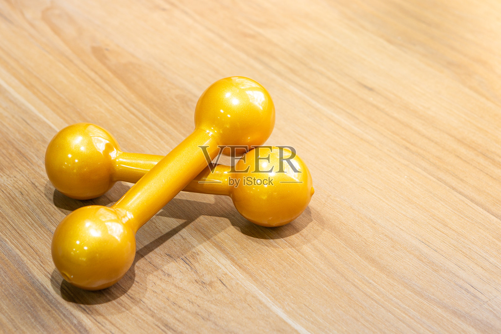 在木地板上练习哑铃。健身房用来举重的金杠铃照片摄影图片