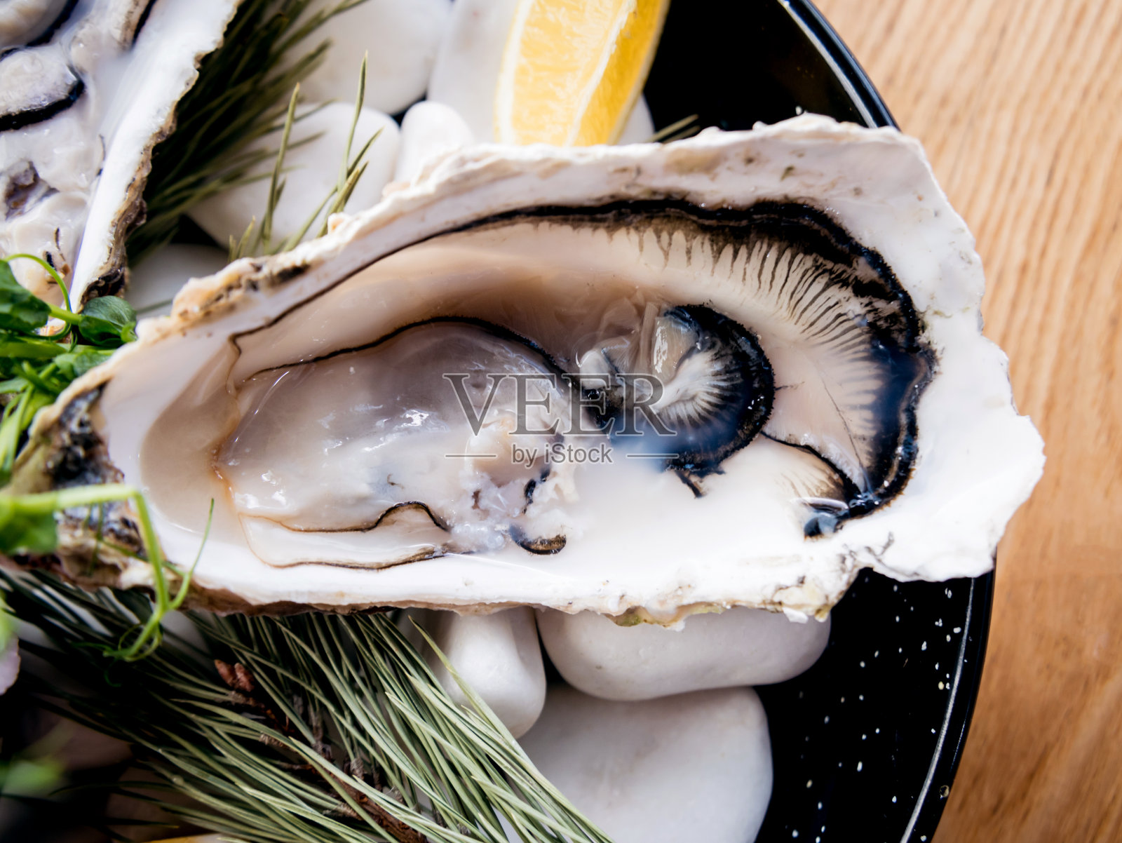 盘子里放着新鲜的牡蛎，还有冰和花。餐厅照片摄影图片