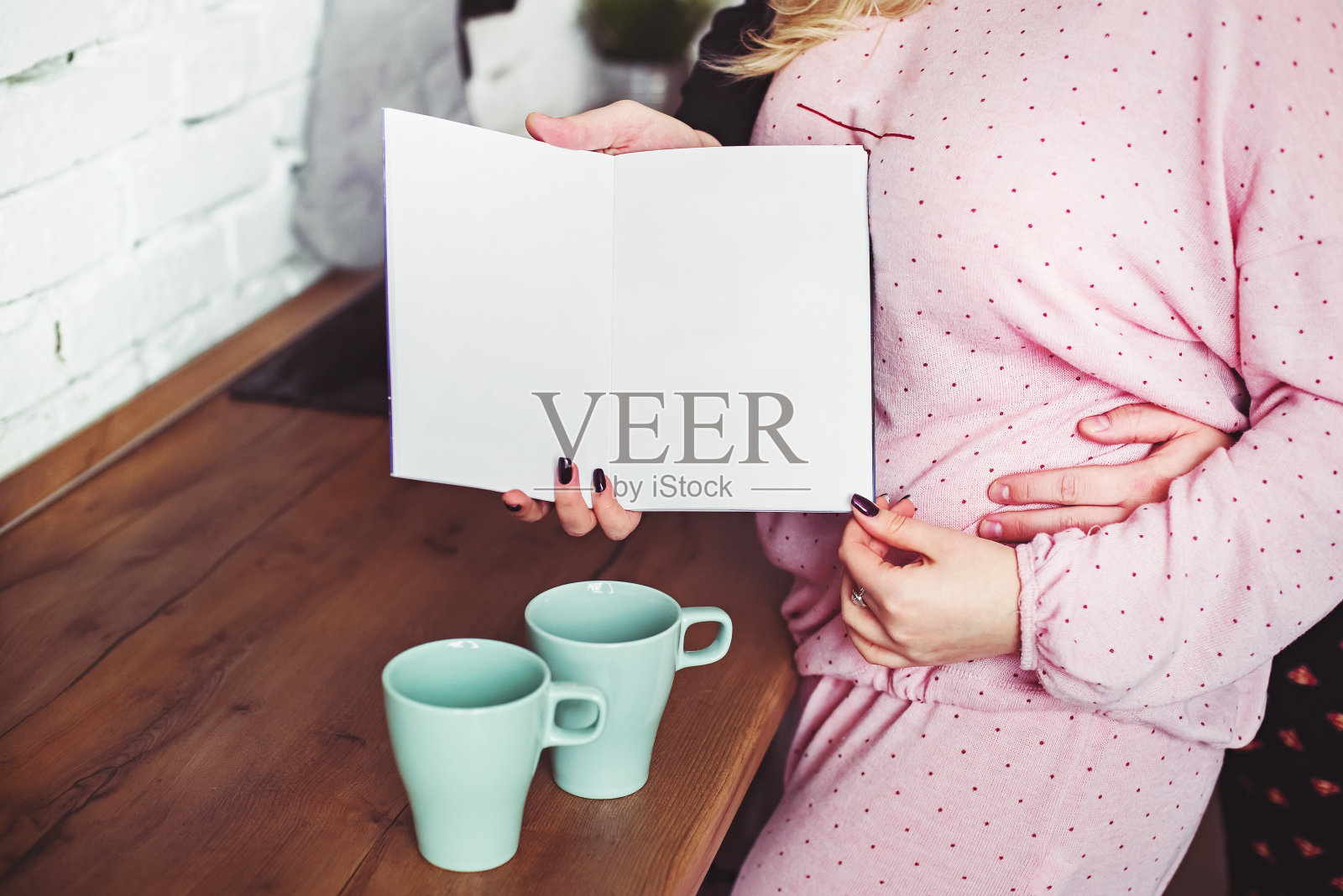 一男一女穿着睡衣，相互拥抱，拿着一本打开的书照片摄影图片