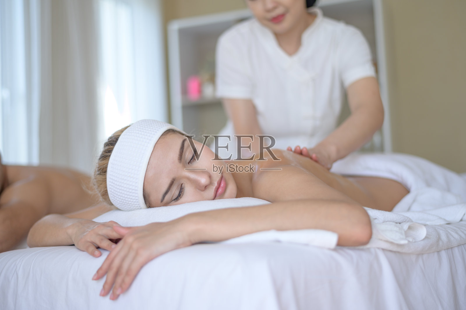 在水疗中心享受面部和头部按摩的漂亮女人照片摄影图片