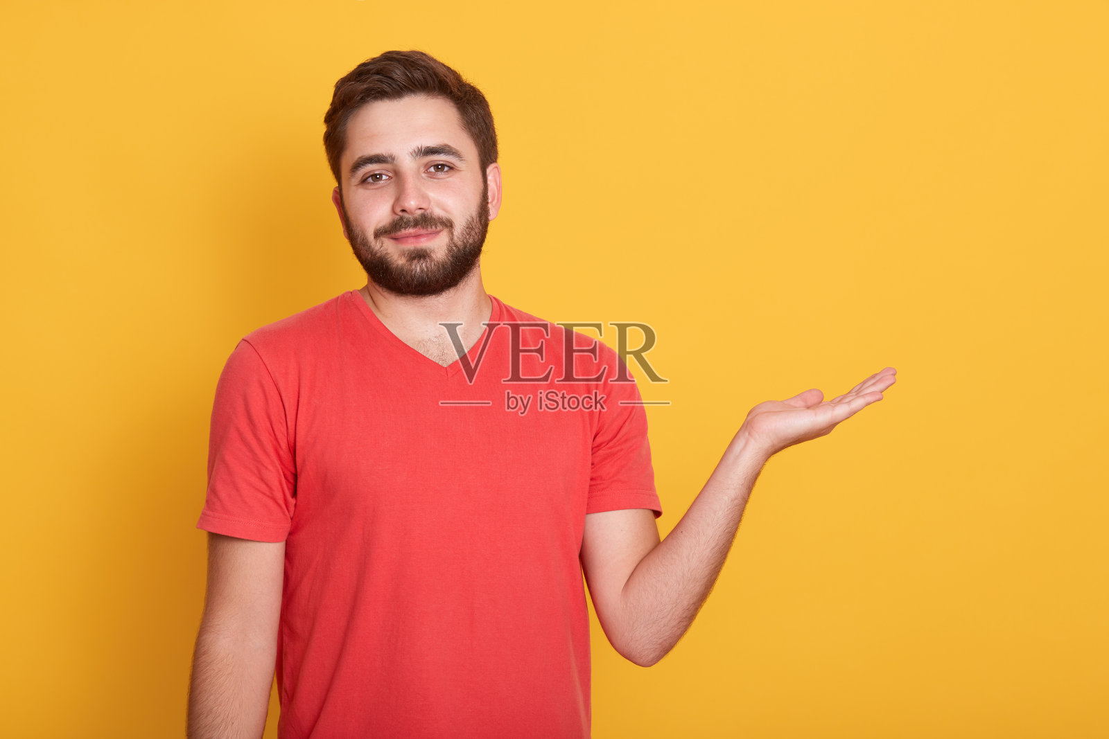 对着镜头微笑的英俊男士，背景为黄色工作室，面部表情平静，举起手，有广告文案空间。照片摄影图片