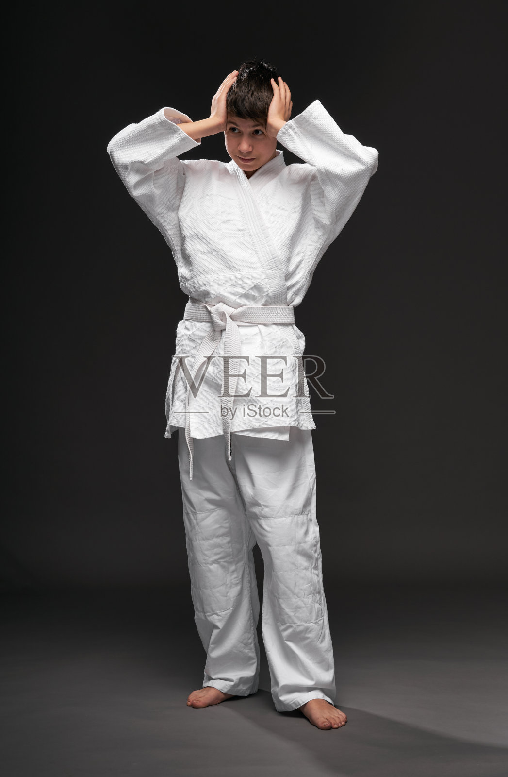 穿着武术服的青少年在深灰色背景上摆姿势，运动概念照片摄影图片