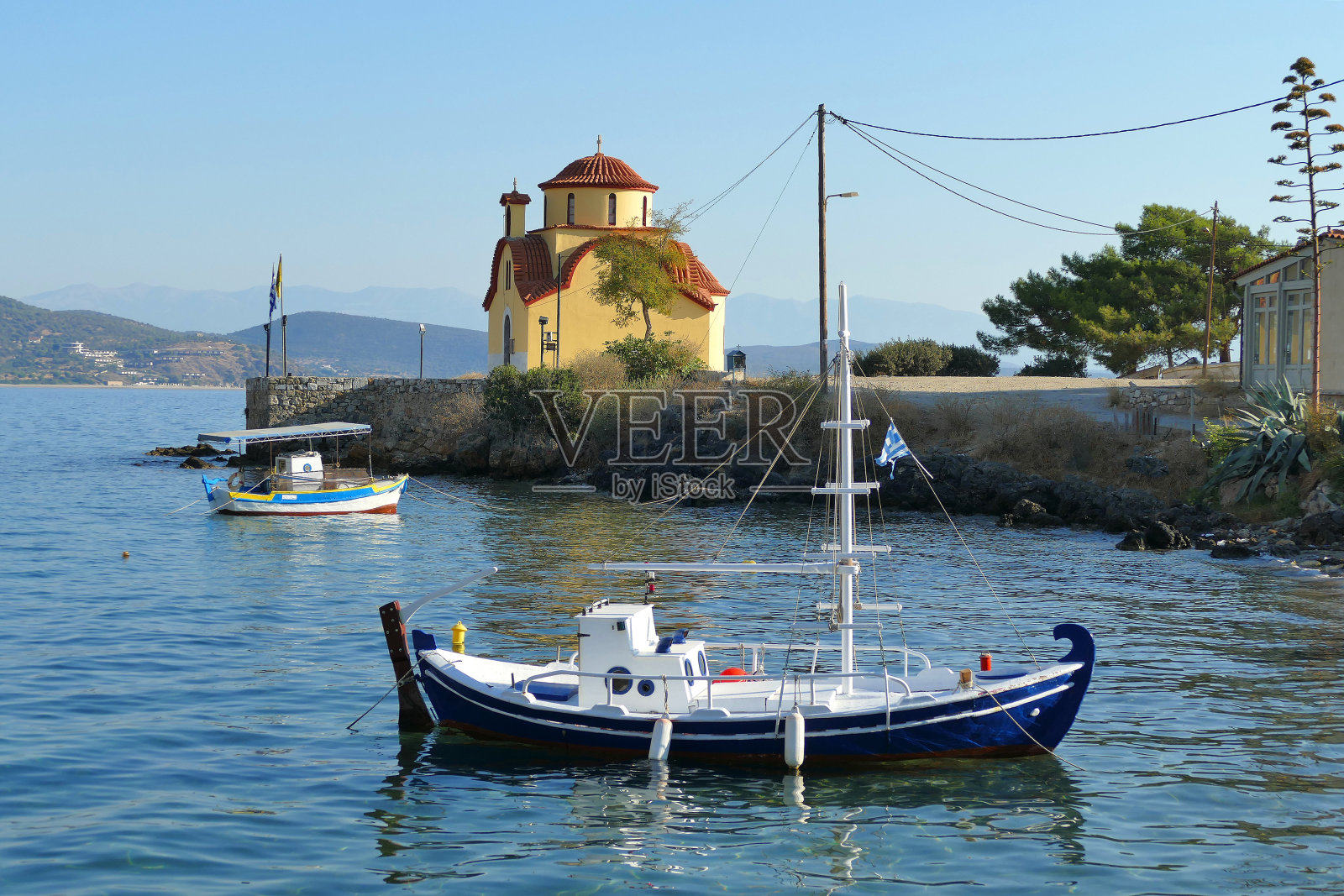 在吉西奥港，小船的背景是一座东正教教堂照片摄影图片