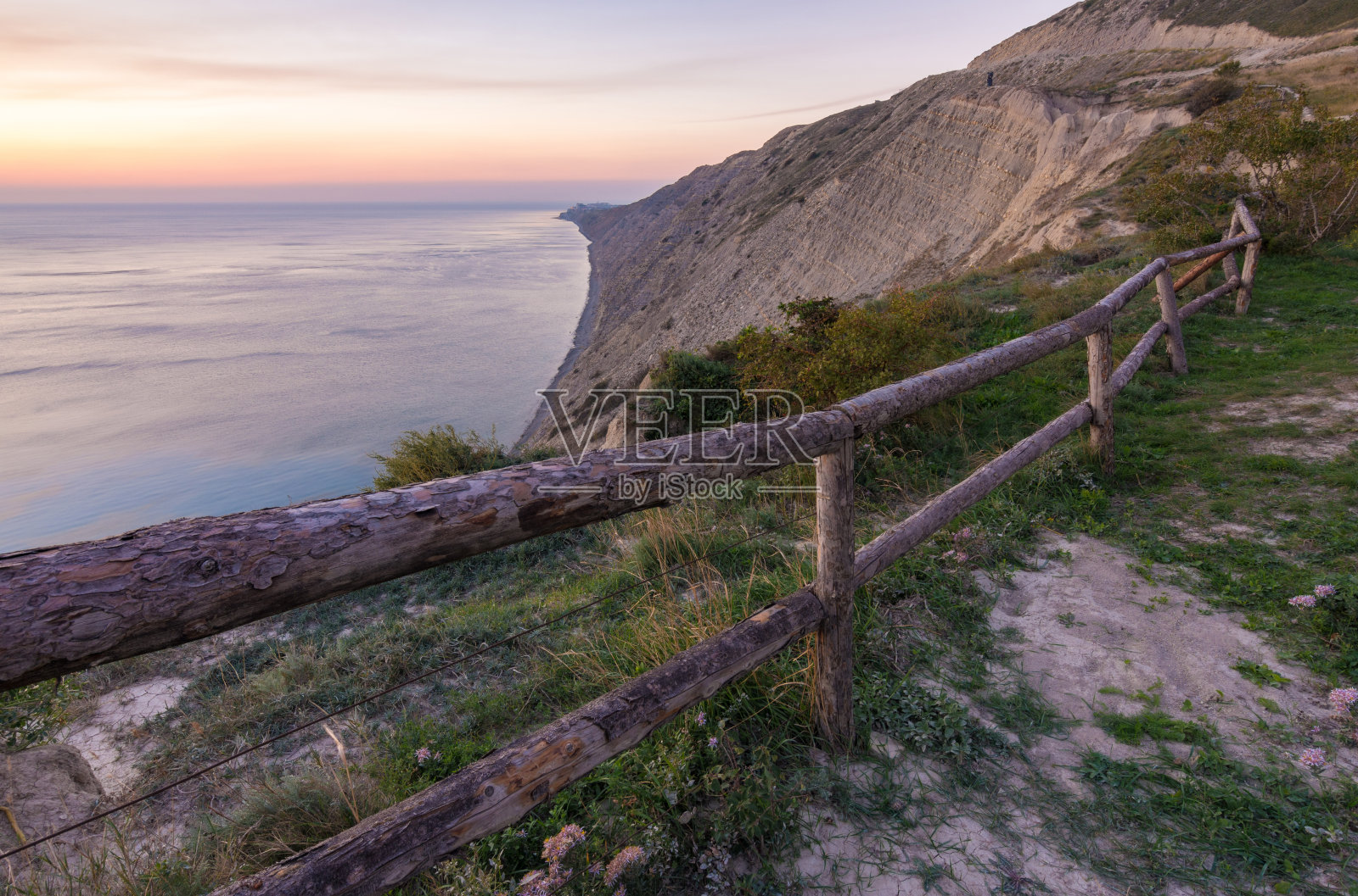 篱笆在多岩石的海岸边的悬崖边用树干围成的篱笆照片摄影图片