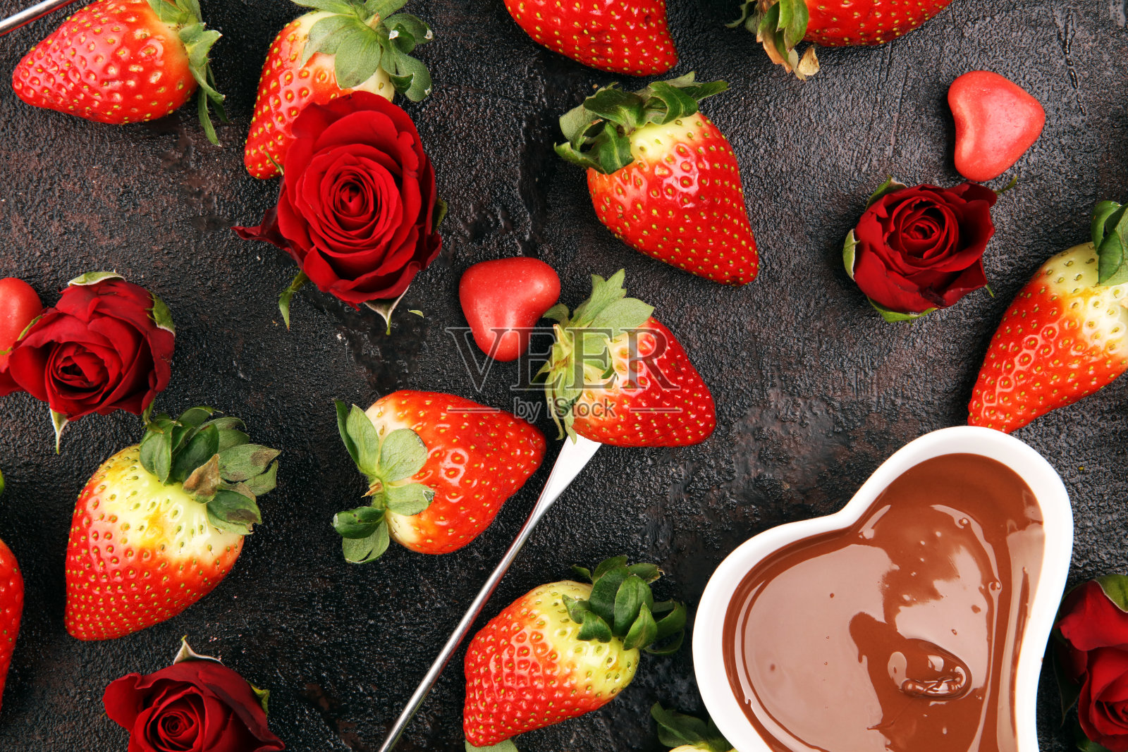 新鲜草莓和黑巧克力和白巧克力融化后的巧克力火锅。情人节的红玫瑰和心形糖。情人节的背景照片摄影图片