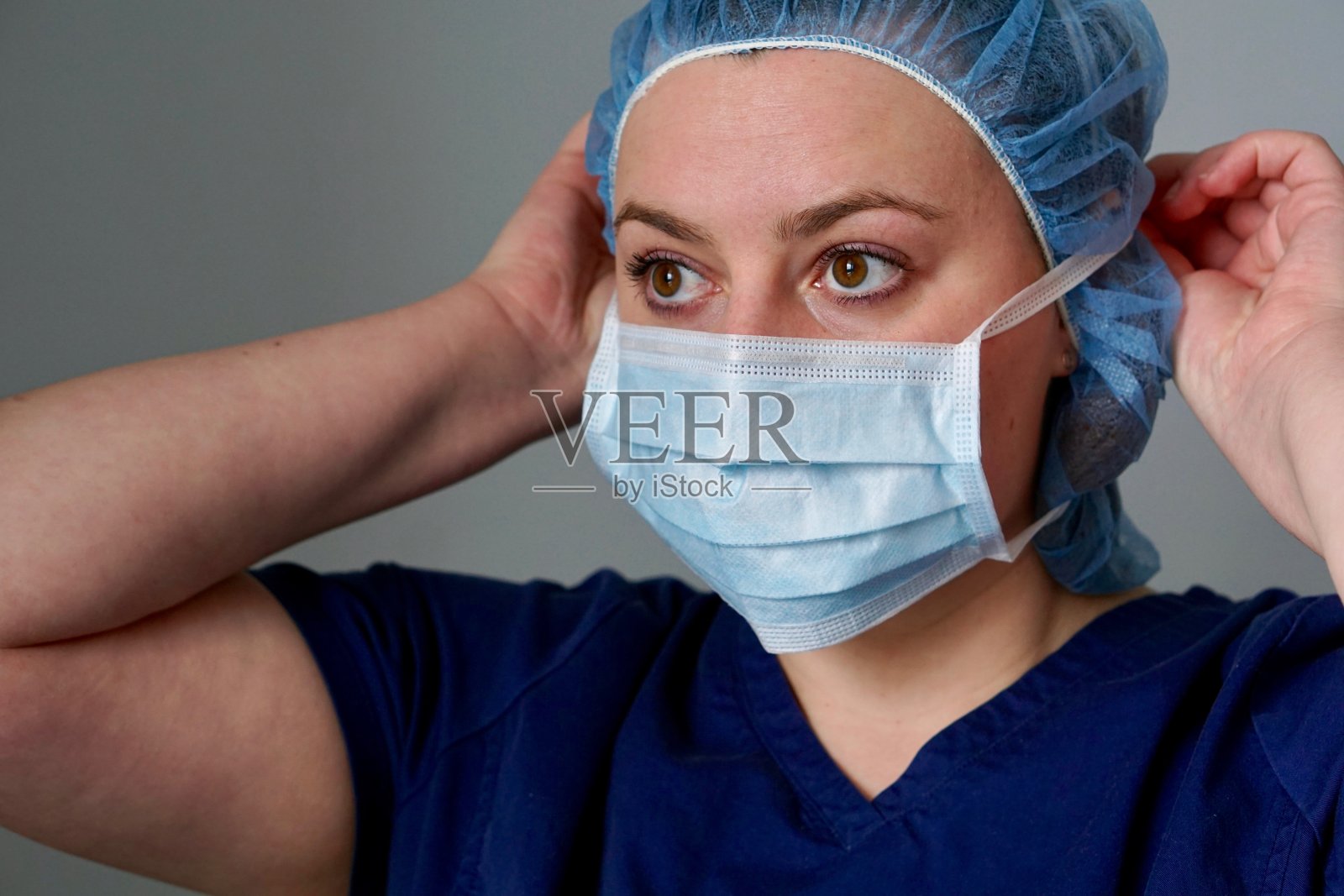 女性外科医生或外科护士戴上口罩准备进入手术室的特写照片摄影图片