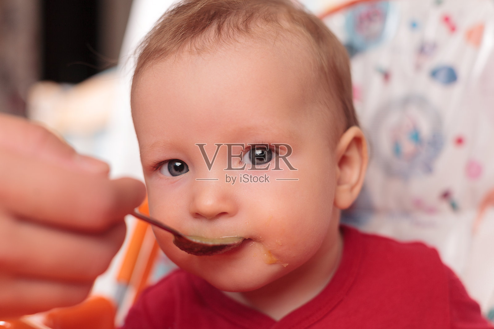 在育儿室里，一个小孩用勺子吃饭，坐着并握住喂食桌的边缘，桌子又脏又沾满了食物，婴儿食品概念，辅助食品照片摄影图片