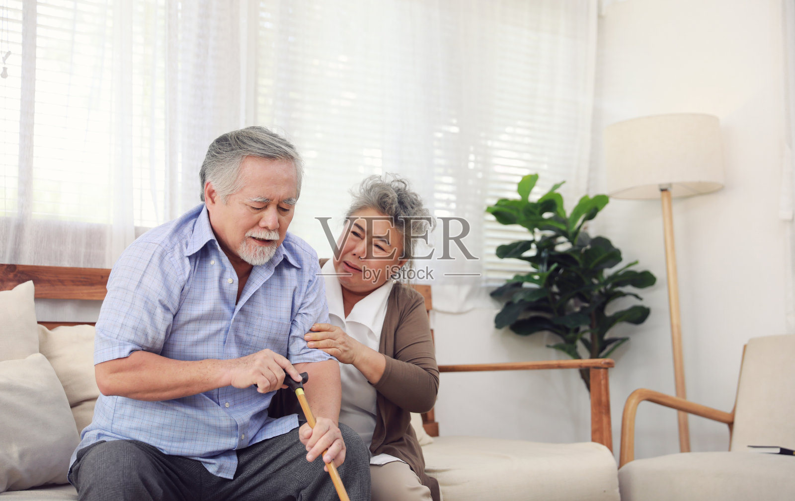 退休夫妇在生病时互相照顾，坐在房子里的沙发上，没有孩子照顾照片摄影图片