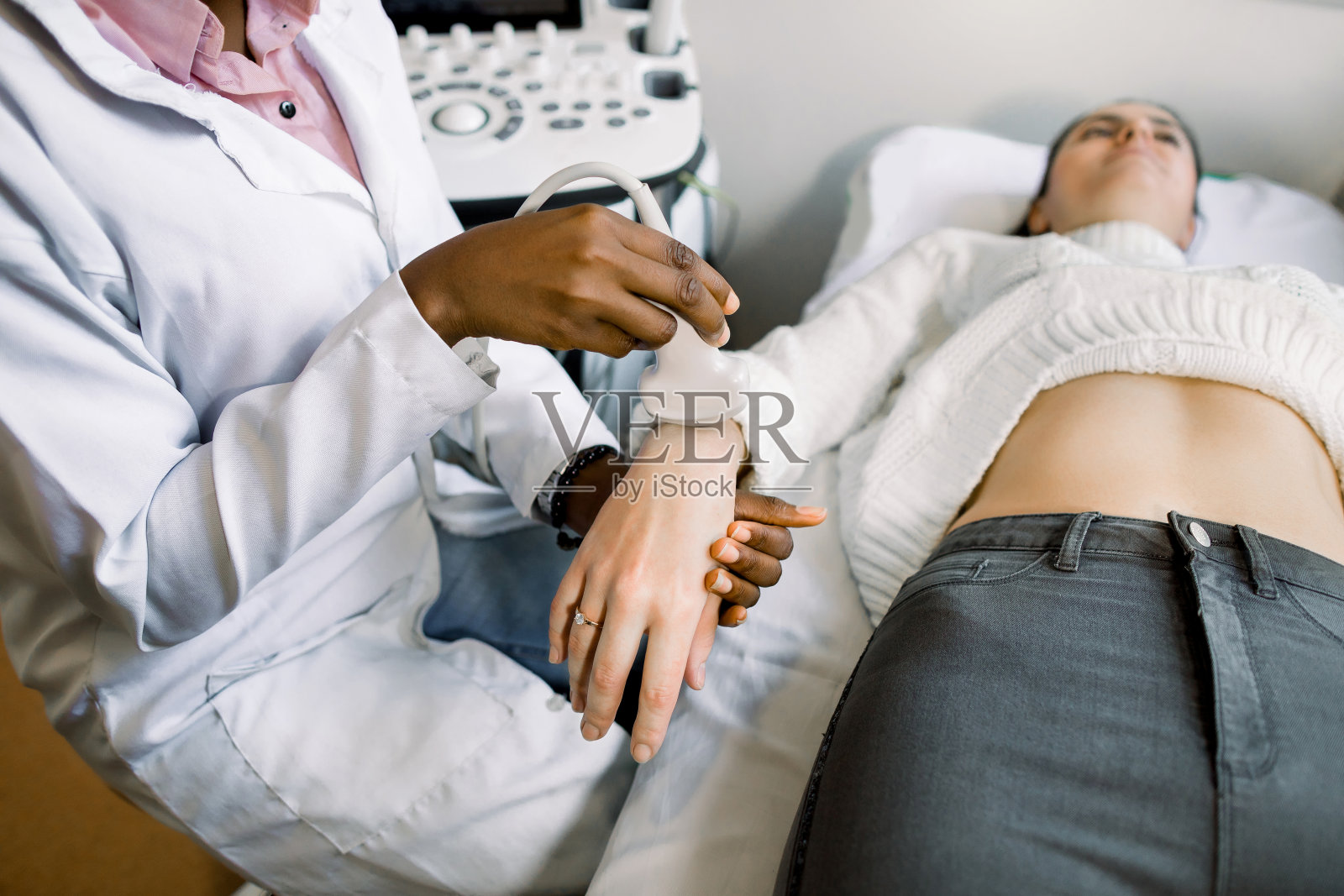 特写非洲女医生的手与超声波扫描仪做检查的年轻女性病人的手照片摄影图片