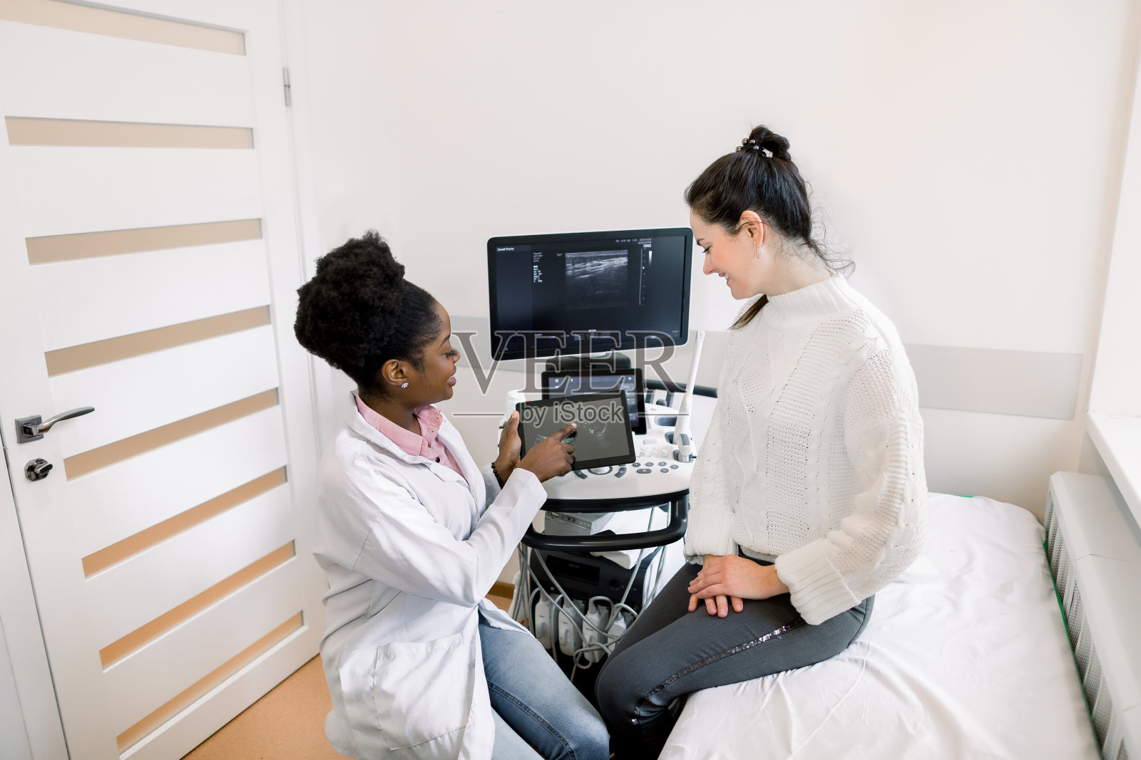 非洲女医生妇科医生在现代医疗办公室向快乐孕妇展示数字平板电脑上的回声超声照片照片摄影图片