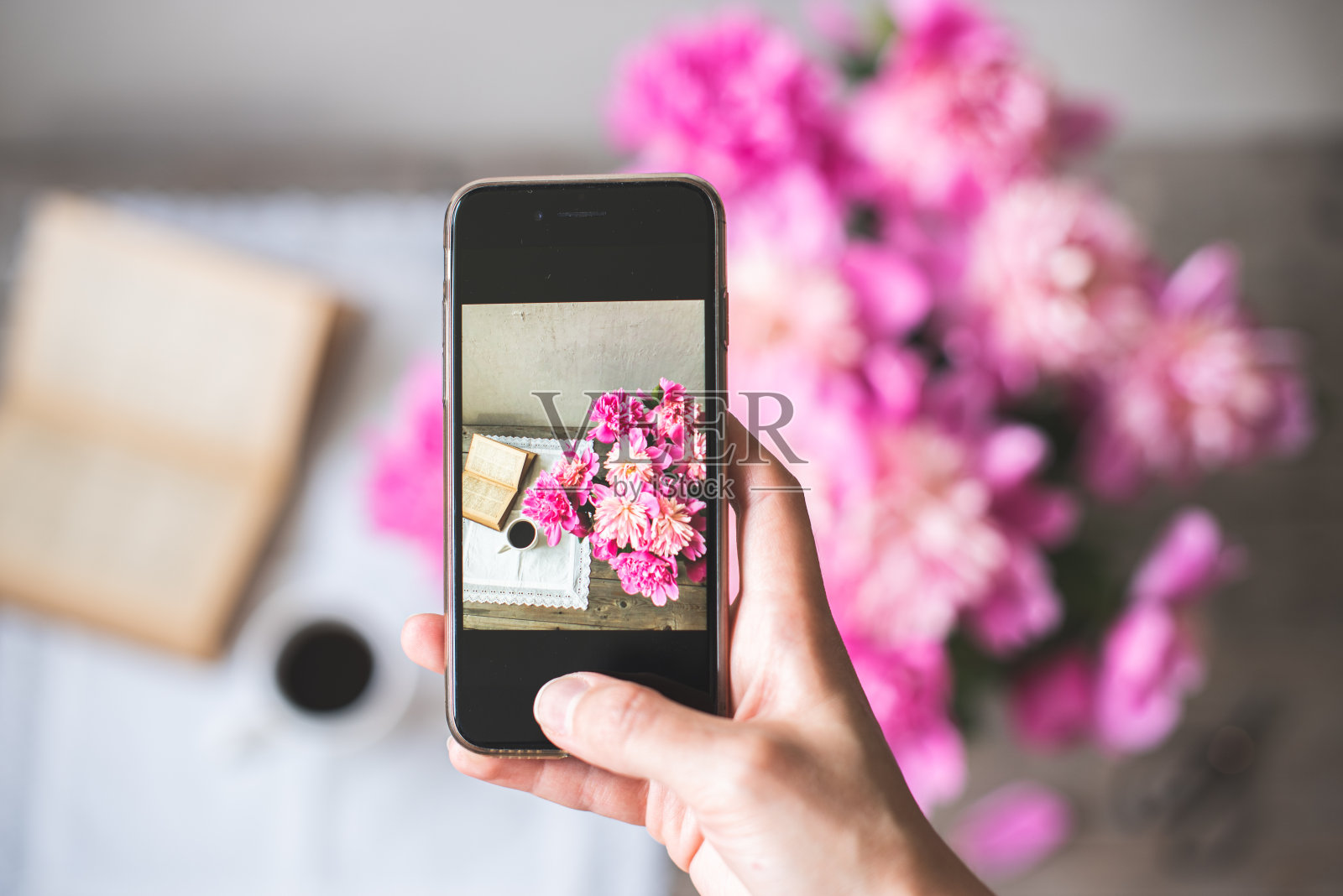 一只女人的手用手机拍摄一束粉红色的牡丹花照片摄影图片