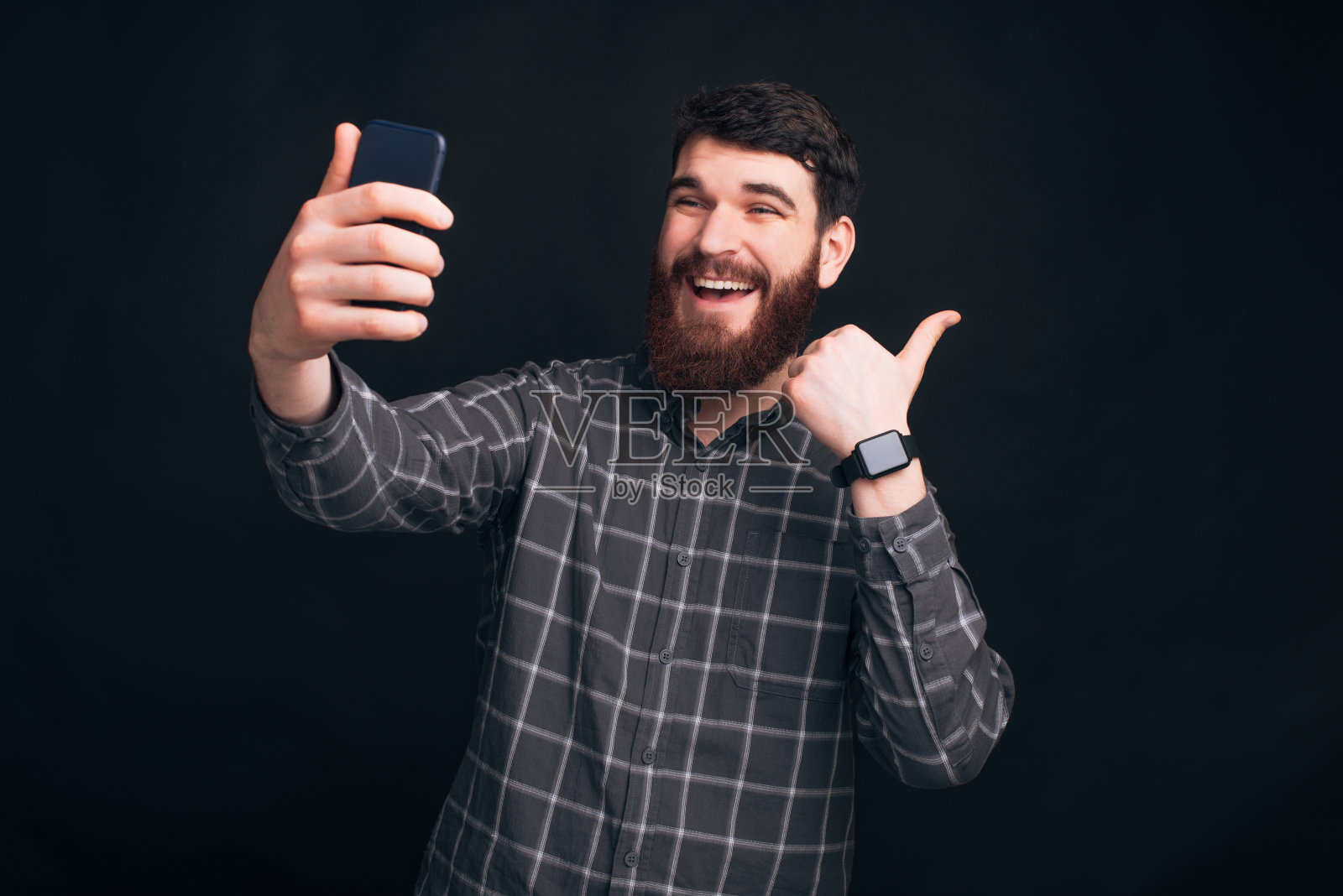 留着胡须、穿着衬衫的年轻男人正在自拍并做出点赞手势照片摄影图片