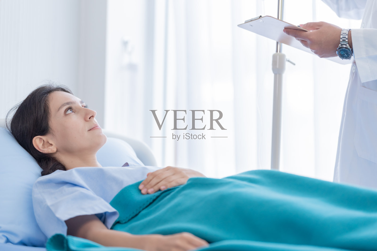 女病人躺在医院病床上听医生讲解照片摄影图片