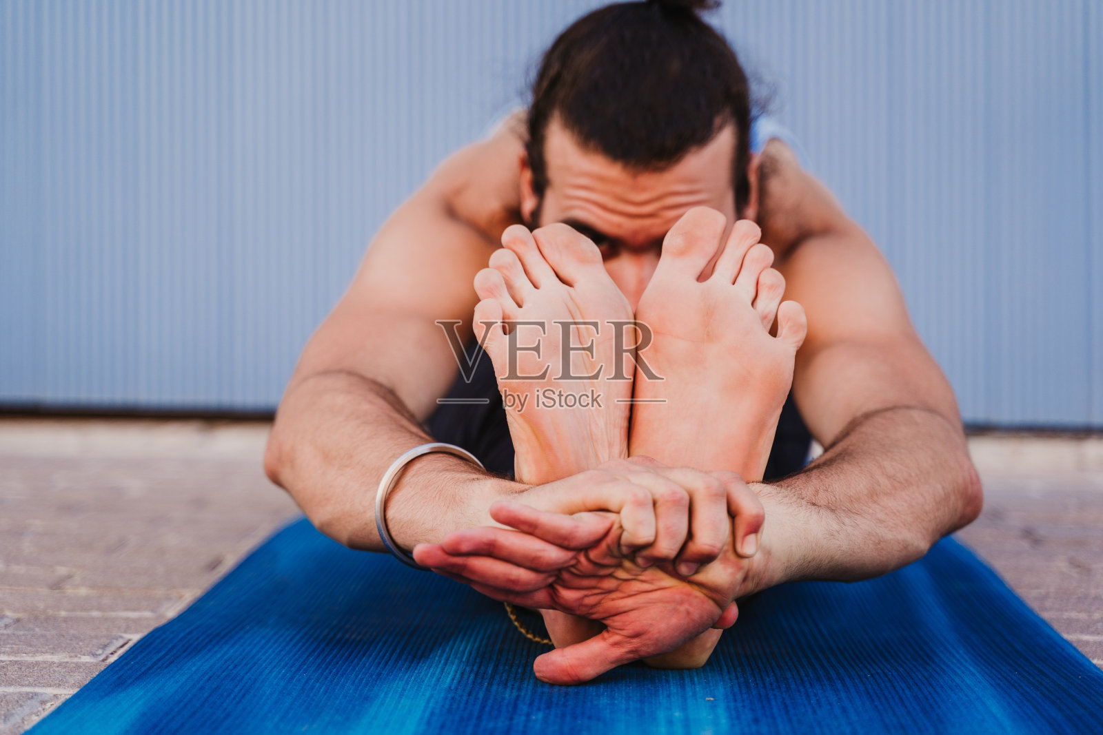 城里有个男人在练瑜伽。蓝色背景。健康的生活方式照片摄影图片