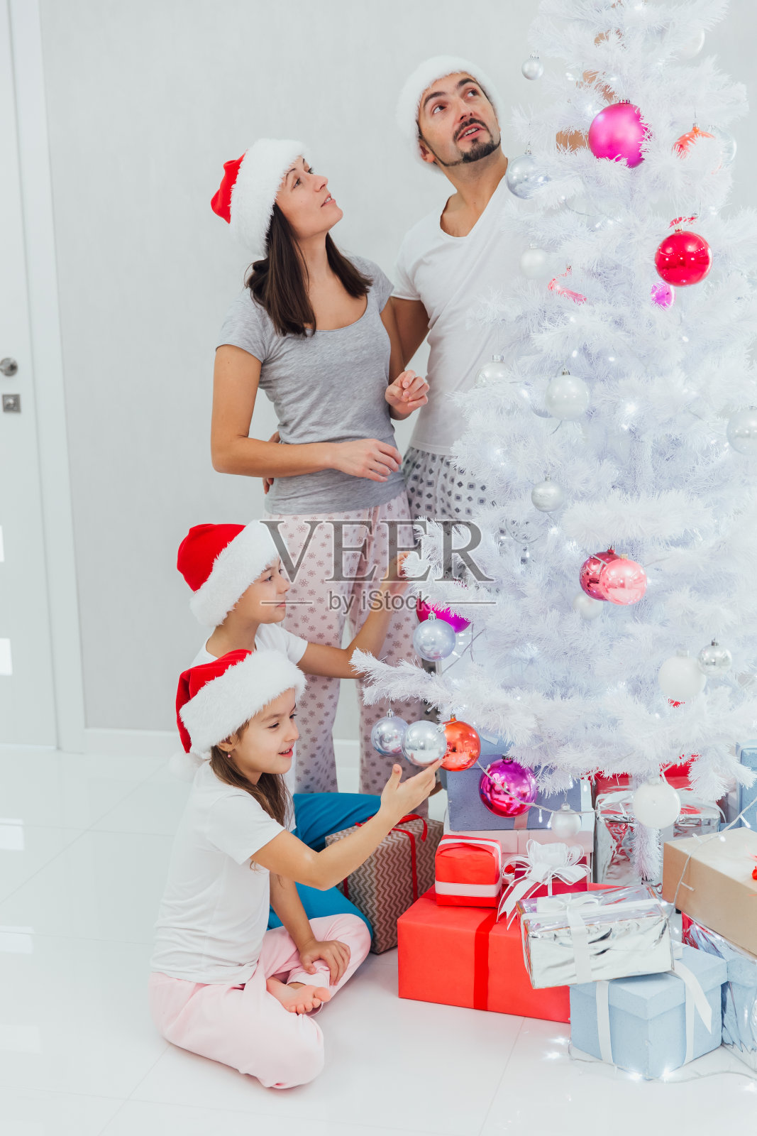 年轻家庭和孩子穿着新年服装在圣诞树旁照片摄影图片