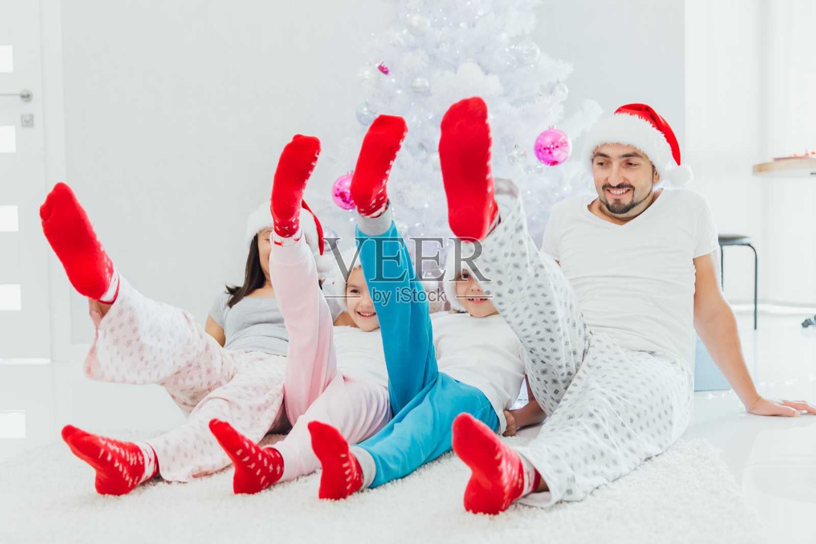 幸福家庭：戴圣诞帽和红袜子的家庭在圣诞树旁的沙发上收礼物照片摄影图片