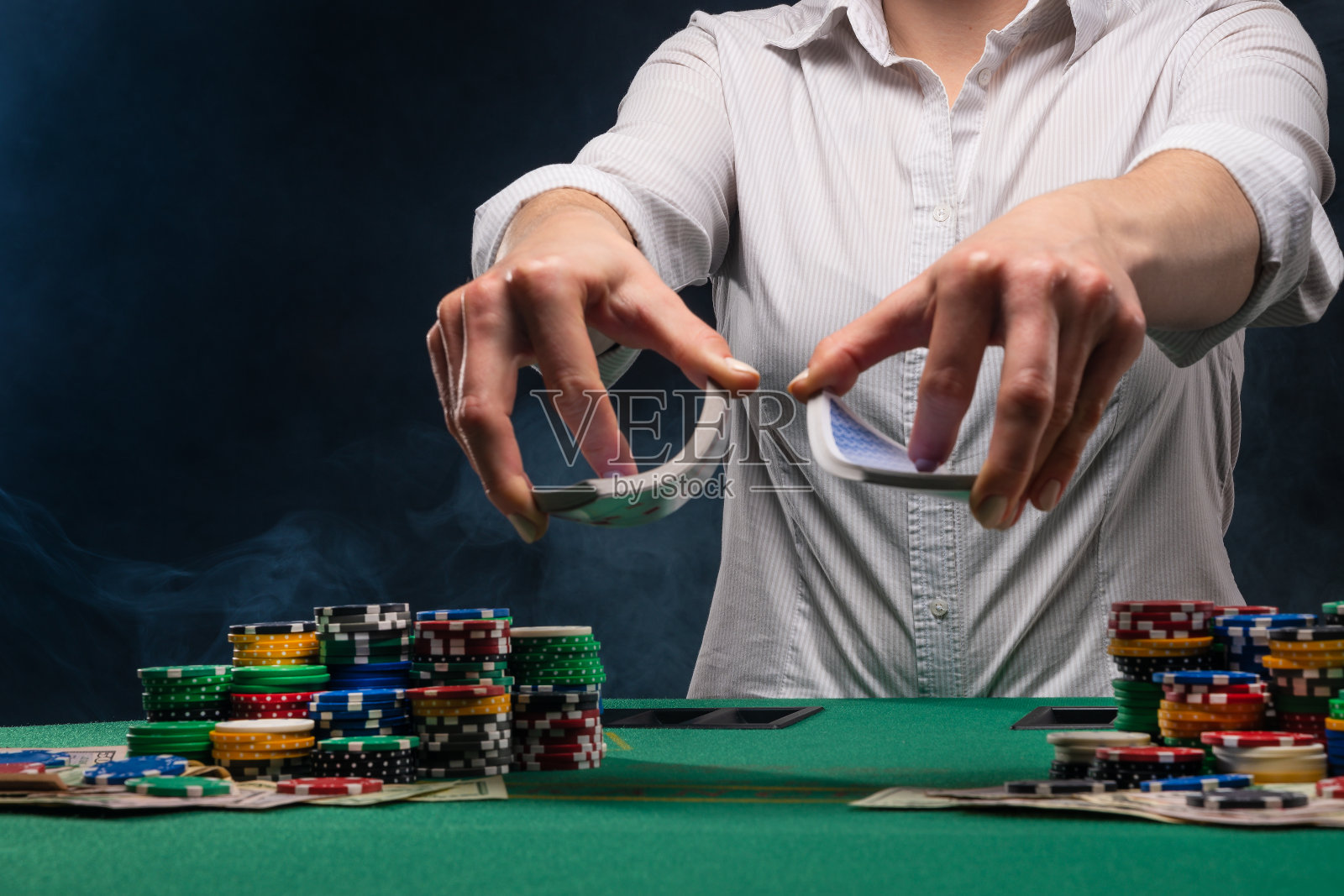 赌场的赌场管理员在玩扑克时，在桌子和筹码的背景下发牌。赌博业在拉斯维加斯照片摄影图片