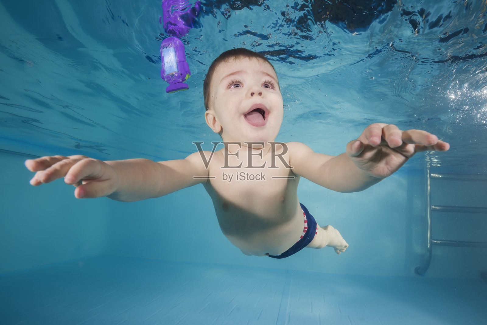 在游泳池里水下玩耍的有趣男孩照片摄影图片