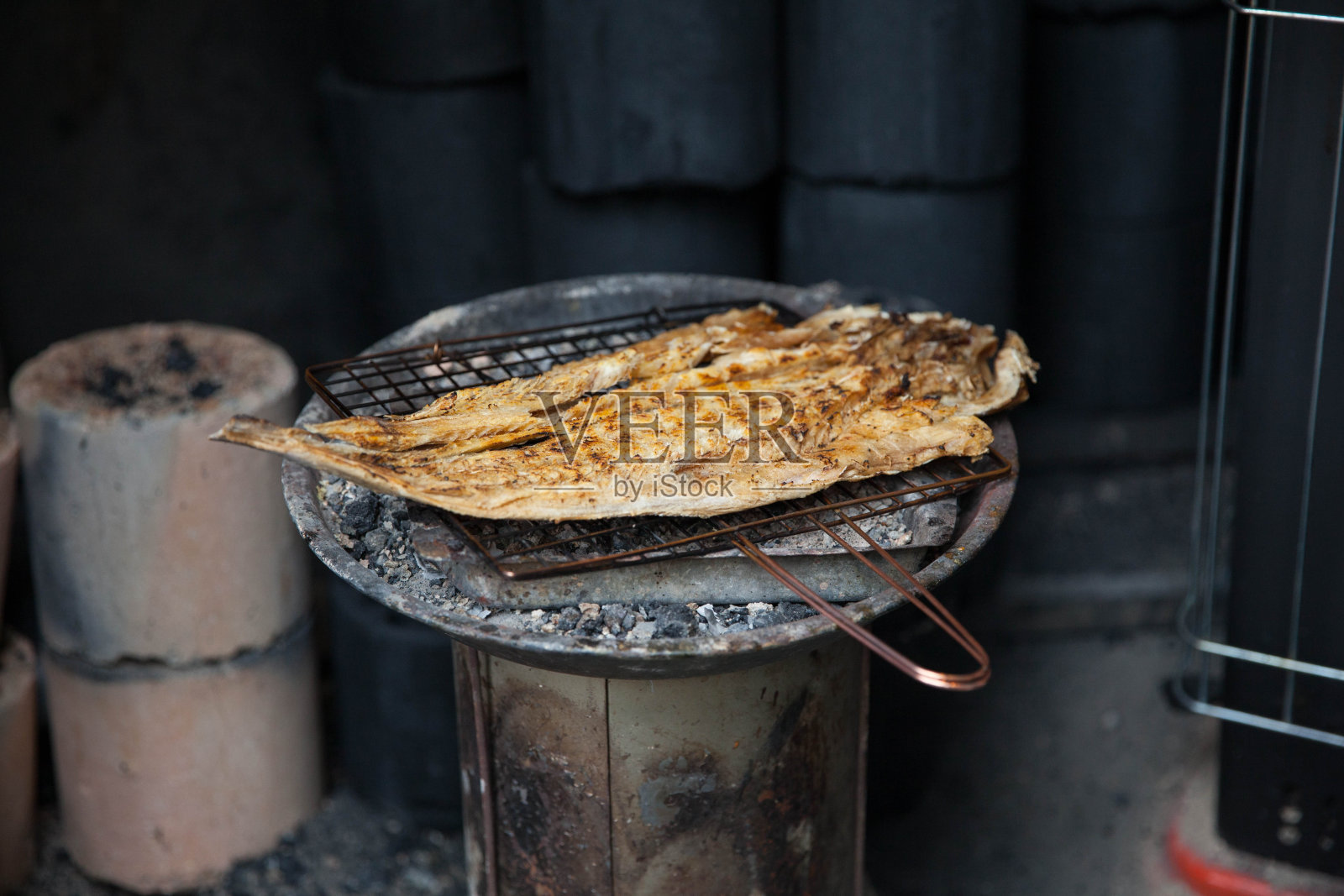 鱼在木炭火上烤在一个小铁丝架上。韩国传统烤鱼干。照片摄影图片