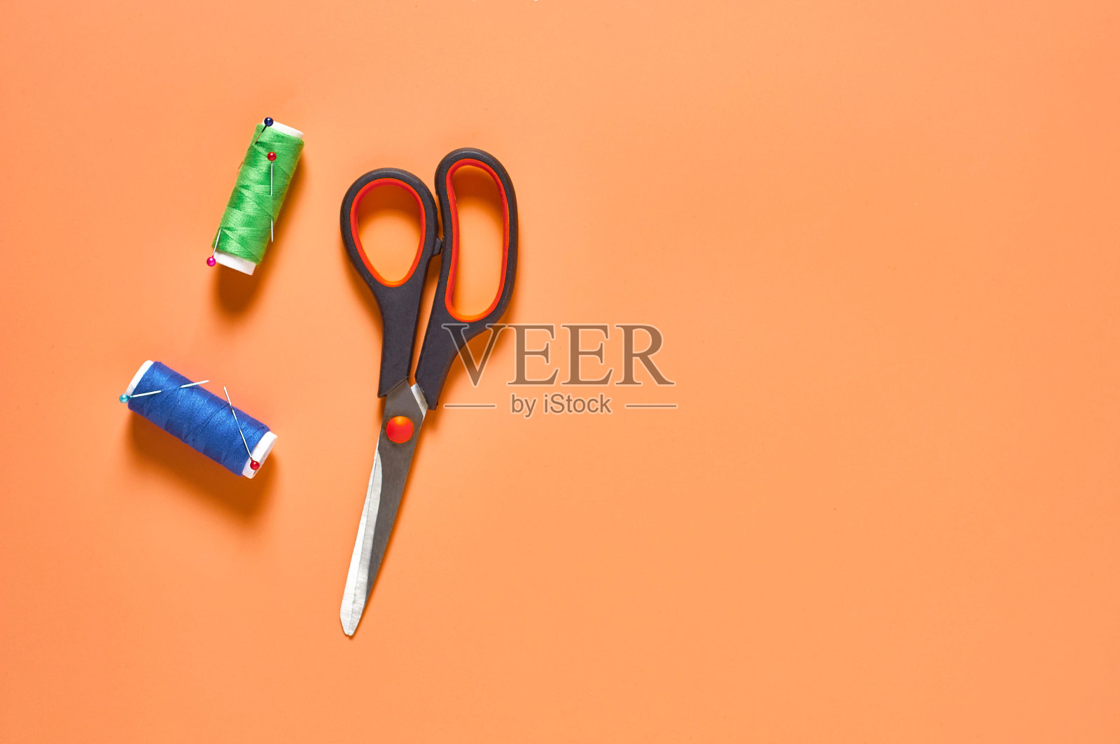 缝纫配件：工作台上带彩色线和针的剪刀及线轴（顶部视图，含文本空间）照片摄影图片