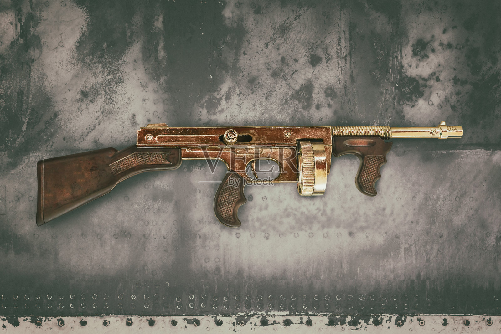 老旧混凝土墙前的复古金色机枪照片摄影图片