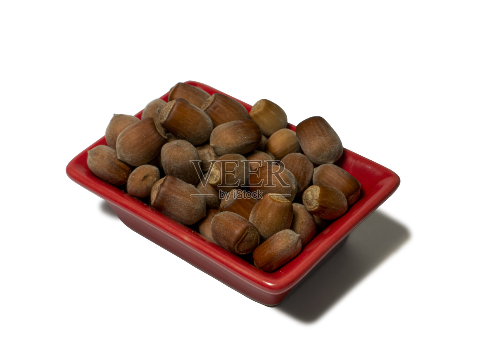 在白色背景上孤立的红色矩形碟子里的榛子。特写镜头照片摄影图片