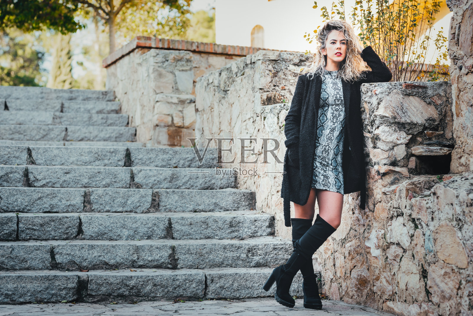 年轻的卷发金发女人，站在楼梯上照片摄影图片