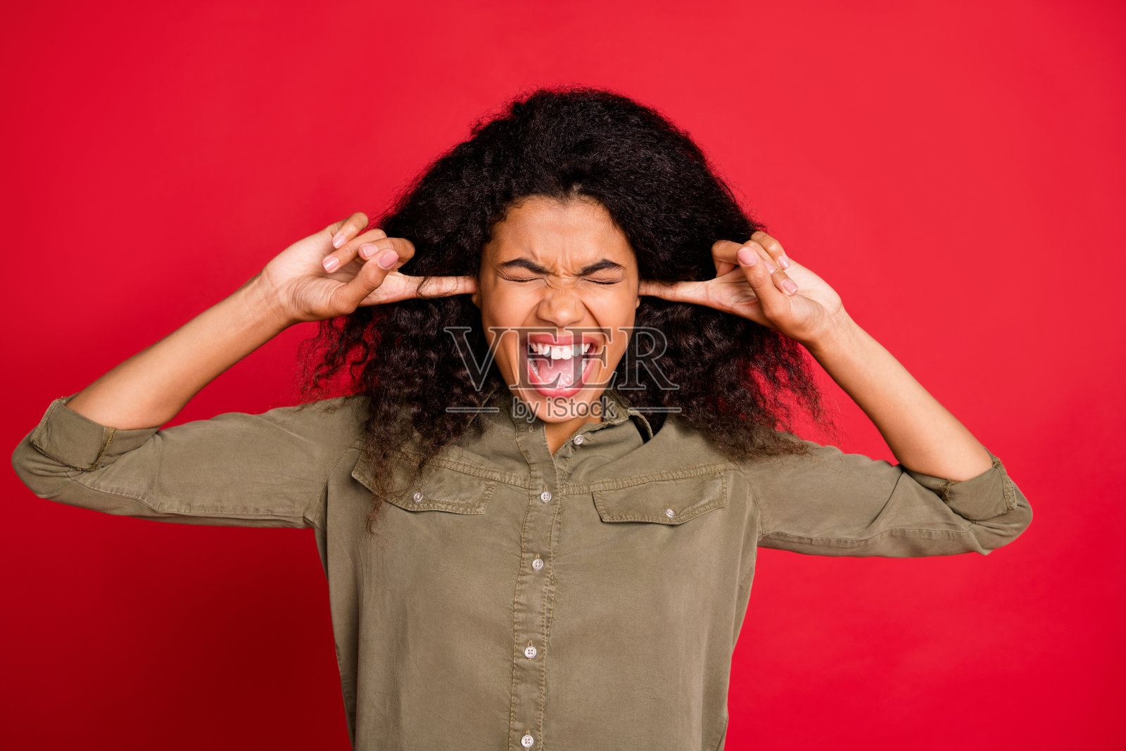 照片上的尖叫，疯狂的愤怒的模特穿着绿色衬衫闭上她的耳朵哭孤立的色彩背景照片摄影图片