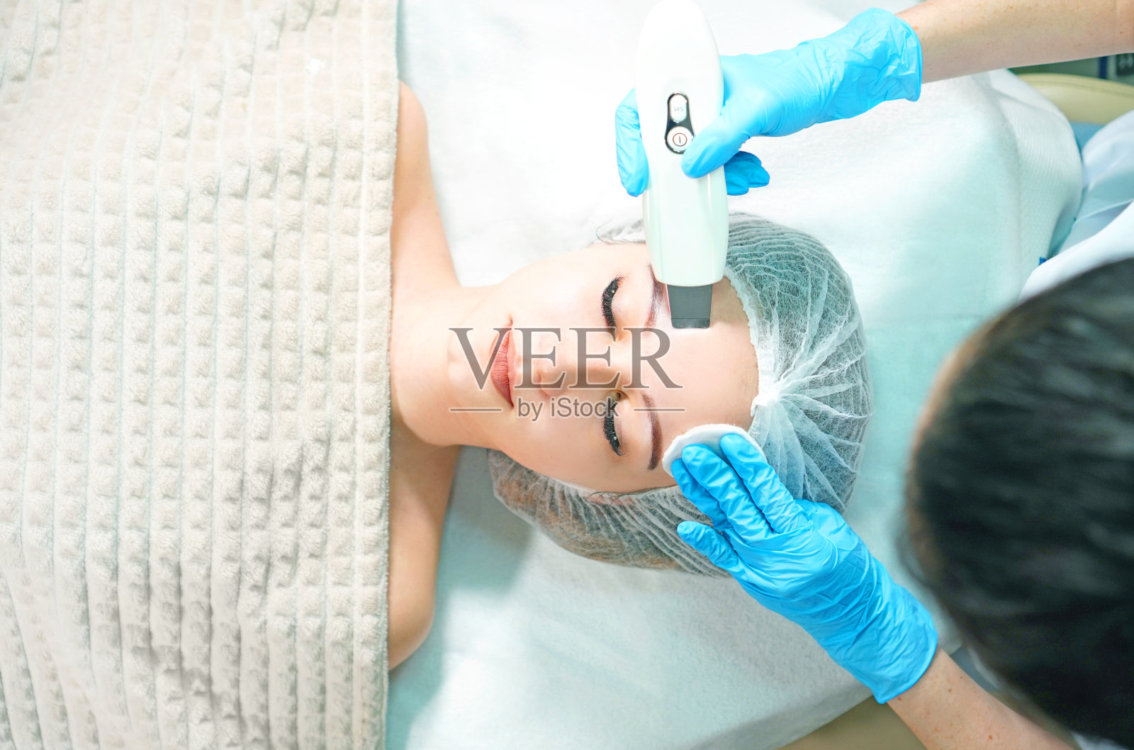 美容师为年轻女子做超声波面部清洁，俯视角度照片摄影图片