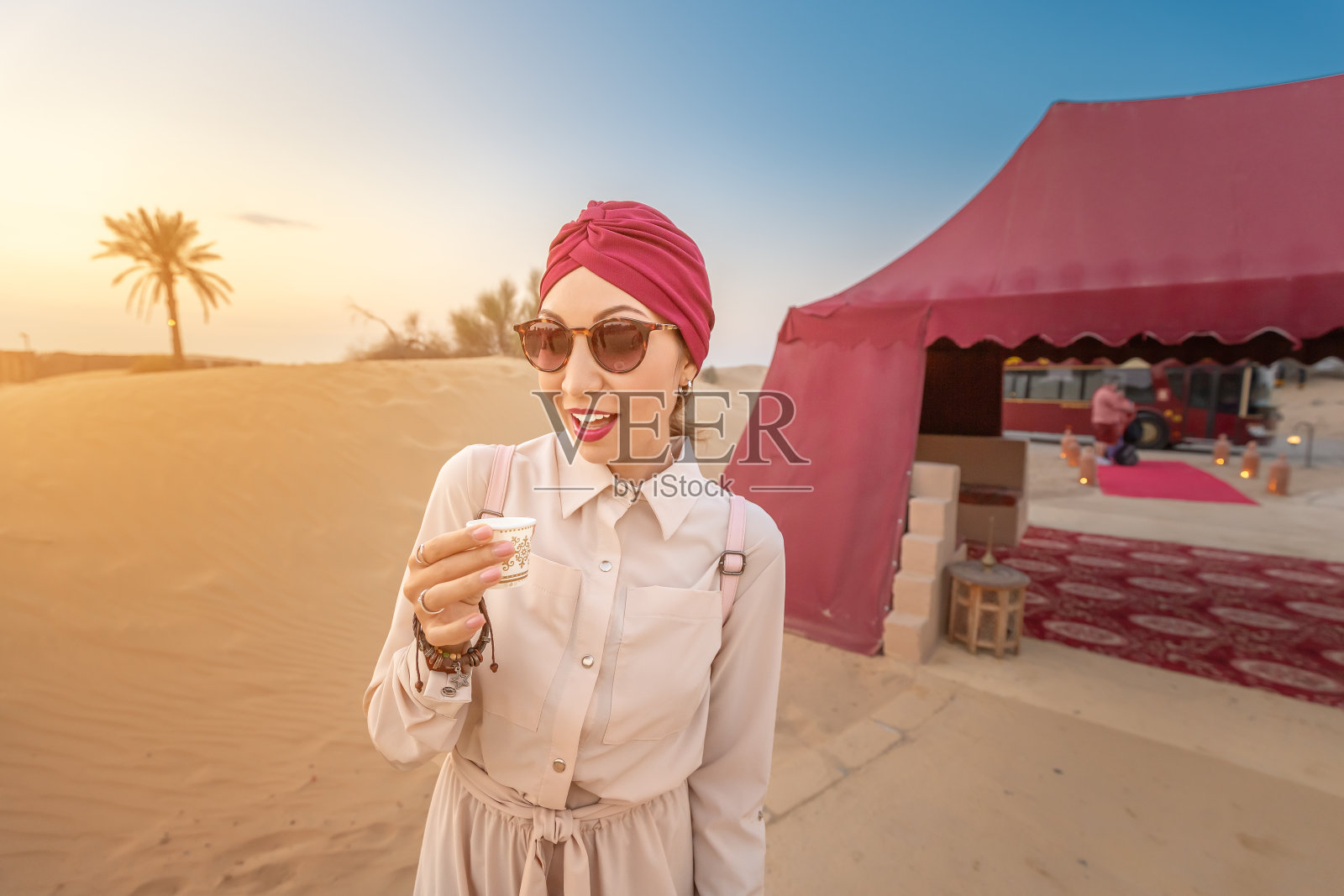 戴着头巾的穆斯林妇女品尝阿拉伯咖啡，同时在中东沙漠旅行和游览照片摄影图片