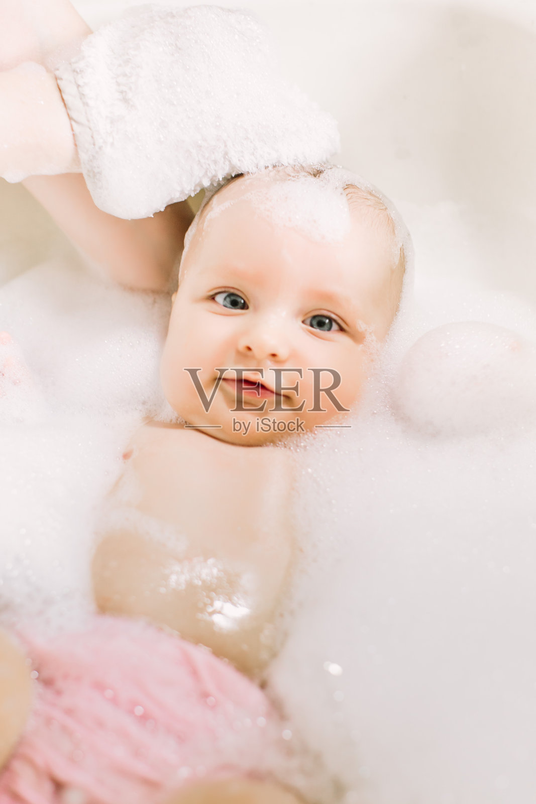 快乐的笑宝宝洗澡玩泡沫泡沫。浴缸里的小孩。婴儿洗浴。卫生和幼儿护理。浴室里婴儿的脸照片摄影图片