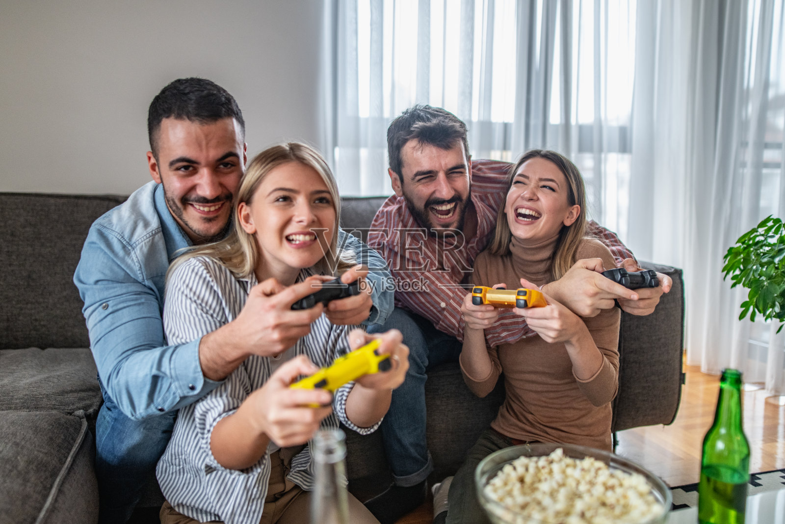 快乐的朋友们在电子游戏中竞争，一起玩乐照片摄影图片
