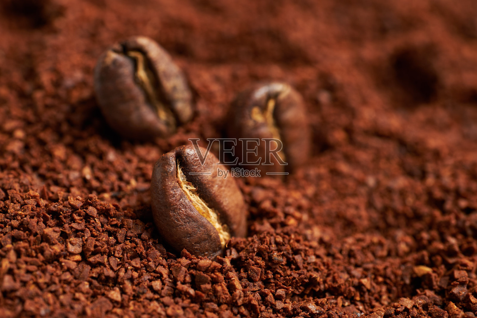 烘好的咖啡豆放在磨碎的咖啡上。照片摄影图片