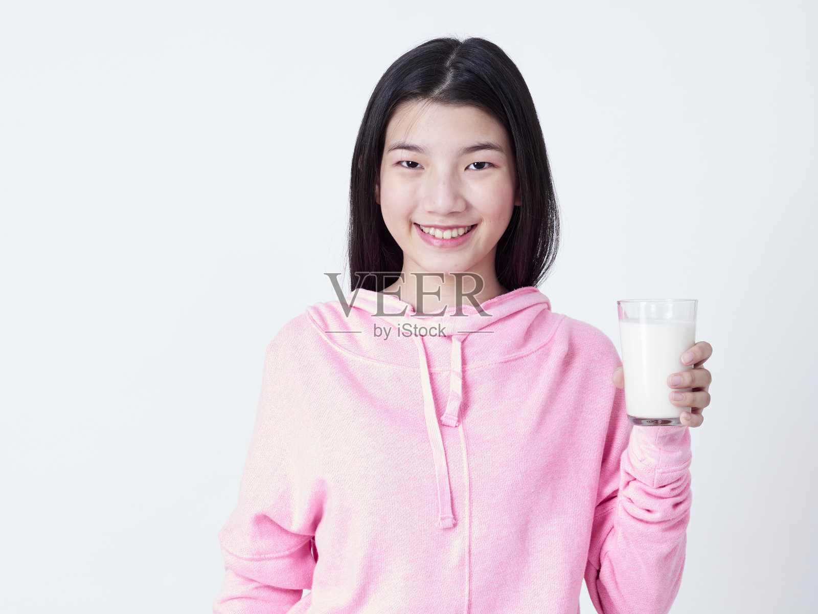 站在白色背景下手拿一杯牛奶的可爱女孩照片摄影图片