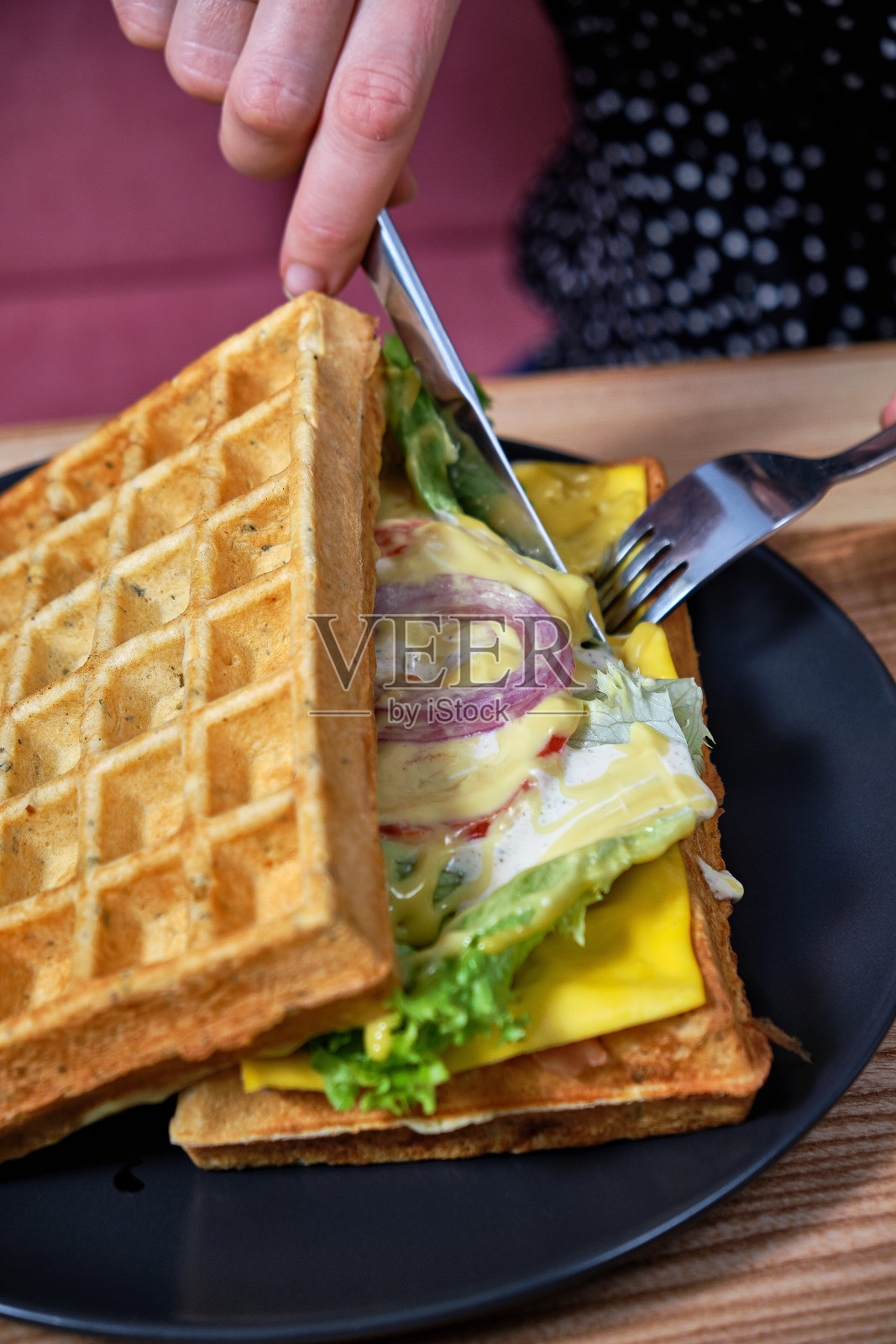 女人用刀叉切夹着鸡肉、生菜和奶酪的薄饼照片摄影图片