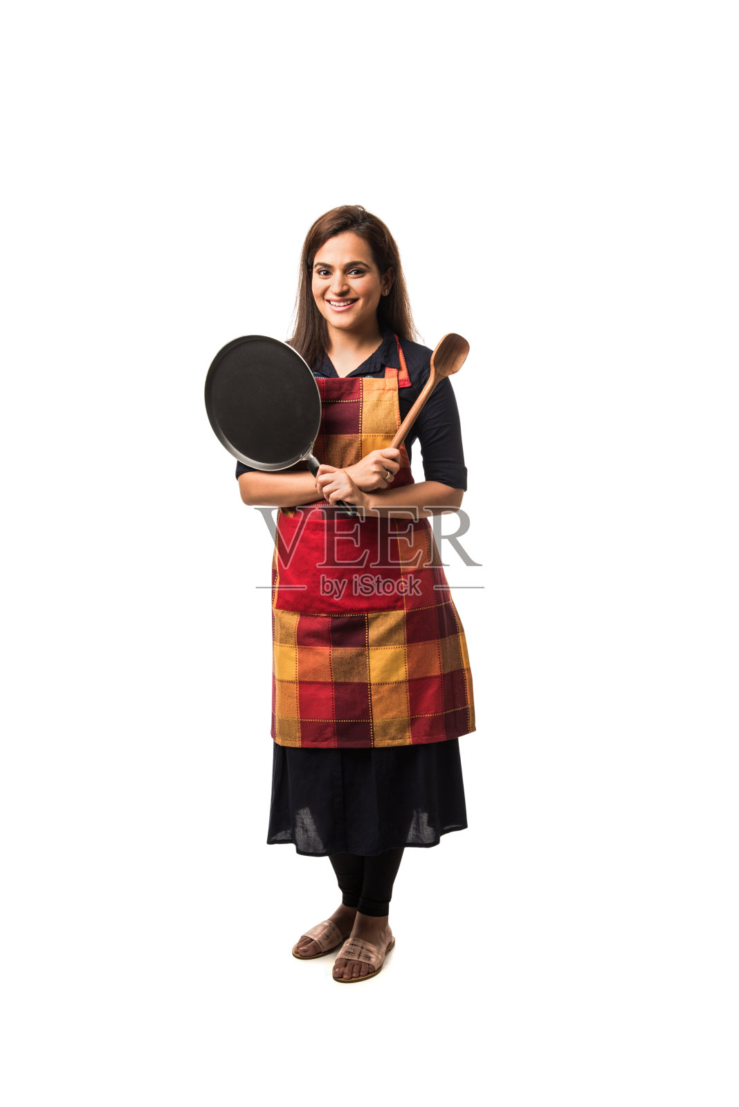 印度/亚洲女厨师，身穿围裙，手持平底锅和铲子，独立站在白色背景前照片摄影图片