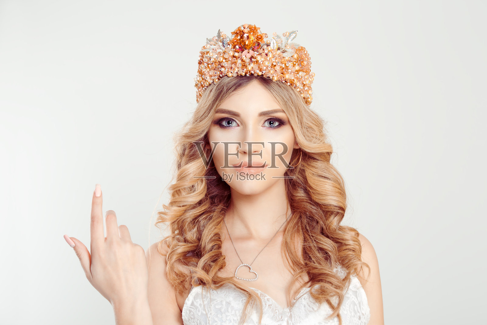 戴王冠的女人用食指指向前方的手势，白色背景照片摄影图片