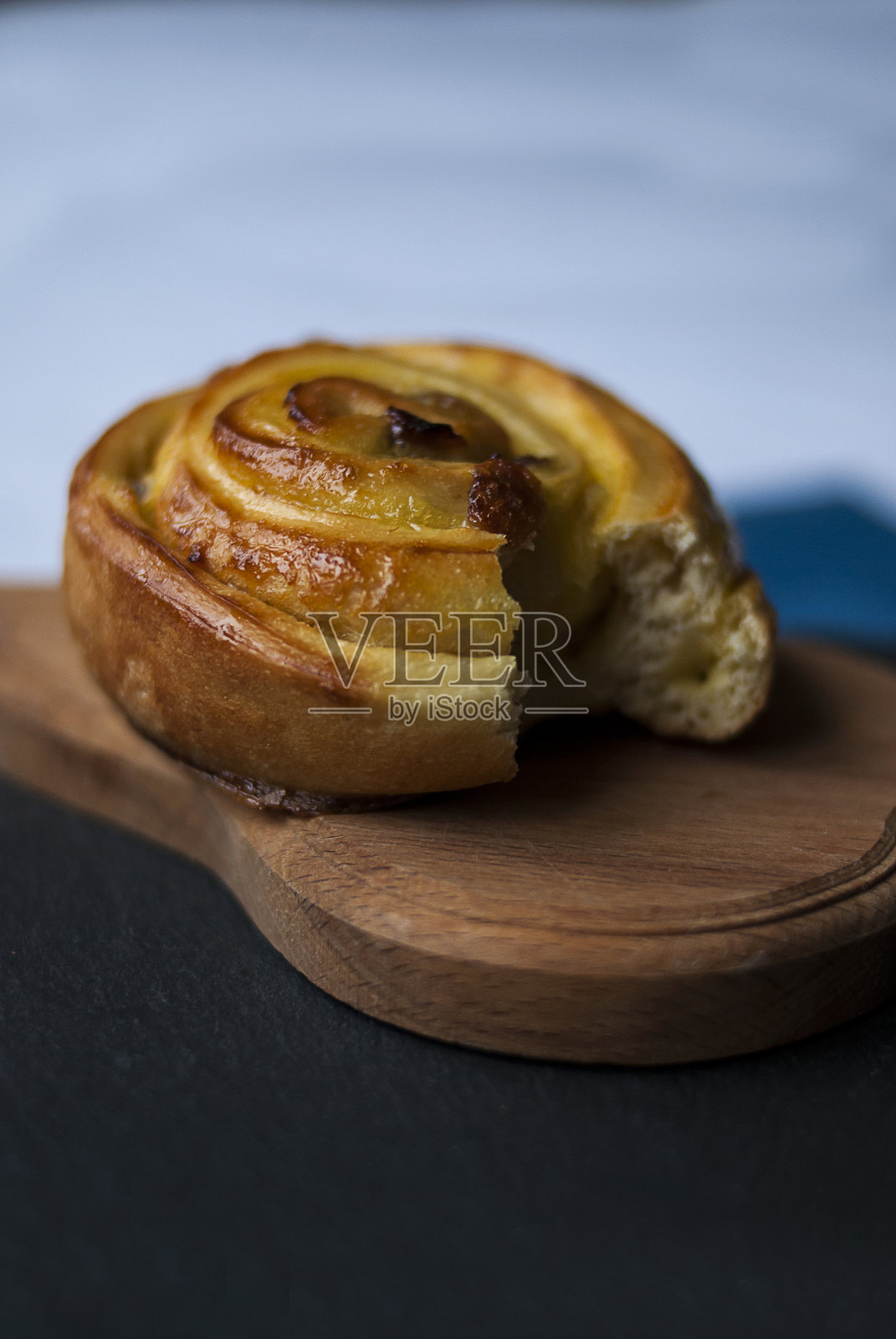 一块木板上放着一块带奶油和葡萄干的小面包照片摄影图片